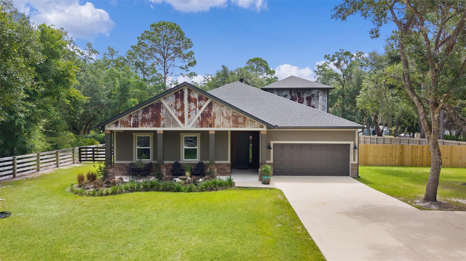 NO HOA | 2022 CUSTOM HOME | FULLY FENCED | POLE BARN | RV HOOKUPS | HIGH-SPEED INTERNET | BOAT ACCESS | NEARLY 1 ACRE. Looking for country living with modern amenities? This custom-built 2022 Craftsman ranch offers the perfect combination of privacy, acreage, storage, and freedom on a fully fenced nearly 1-acre property in desirable Weirsdale. Bring your RV, boat, trailers, work trucks, recreational vehicles, and outdoor toys—there's room for all of it and no HOA restrictions. Featuring 4 bedrooms, 2 full baths, 2 half baths, plus a finished bonus room with its own bath and closet, this home was thoughtfully designed for families, remote workers, multigenerational living, and buyers seeking a rural lifestyle without sacrificing convenience. Inside, the home showcases exceptional custom craftsmanship and modern design.  You'll find 10-foot ceilings, 8-foot doors, an open-concept floor plan, stained concrete flooring in the main living areas, custom shutters, upgraded lighting, a wood-burning fireplace and stunning live-edge cedarwood staircase. The chef's kitchen is built for entertaining with granite countertops, soft-close maple cabinetry, Samsung stainless steel appliances, a huge center island, and a custom walk-in pantry. The spacious private owner's suite features a zero-entry tiled shower designed for long-term comfort and accessibility, dual vanities, and a large walk-in closet with custom wood closet systems throughout. Outside this property truly shines. The fully fenced yard includes a large 40x60 5-stall pole barn, 10x16 storage shed, drive-through driveway with solar-powered gates, dedicated pet area, whole-house generator hookup, 30- and 50- amp RV service, overhead garage storage, private well, irrigation system, and ADT security system. Dedicated high-speed internet makes working from home easy while enjoying the peace and quiet of country life.  Located in Flood Zone X, this property offers added peace of mind. Outdoor enthusiasts will love being just two minutes from boat access to the Ocklawaha River, with direct access to Silver Springs and the Harris Chain of Lakes. Enjoy boating, fishing, kayaking, wildlife viewing, in one of Central Florida's most desirable freshwater recreation corridors.  Conveniently located near The Villages, Eustis, and Mount Dora, you'll enjoy the privacy of rural living with shopping, dining, healthcare, and entertainment just minutes away. Rarely do newer construction homes offer this combination of acreage, privacy, no HOA, boat access, RV accommodations, high-speed internet, and extensive outbuildings. Whether you're seeking a homestead, hobby farm, outdoor retreat, or simply more space to live the lifestyle you want, this property checks all the boxes.