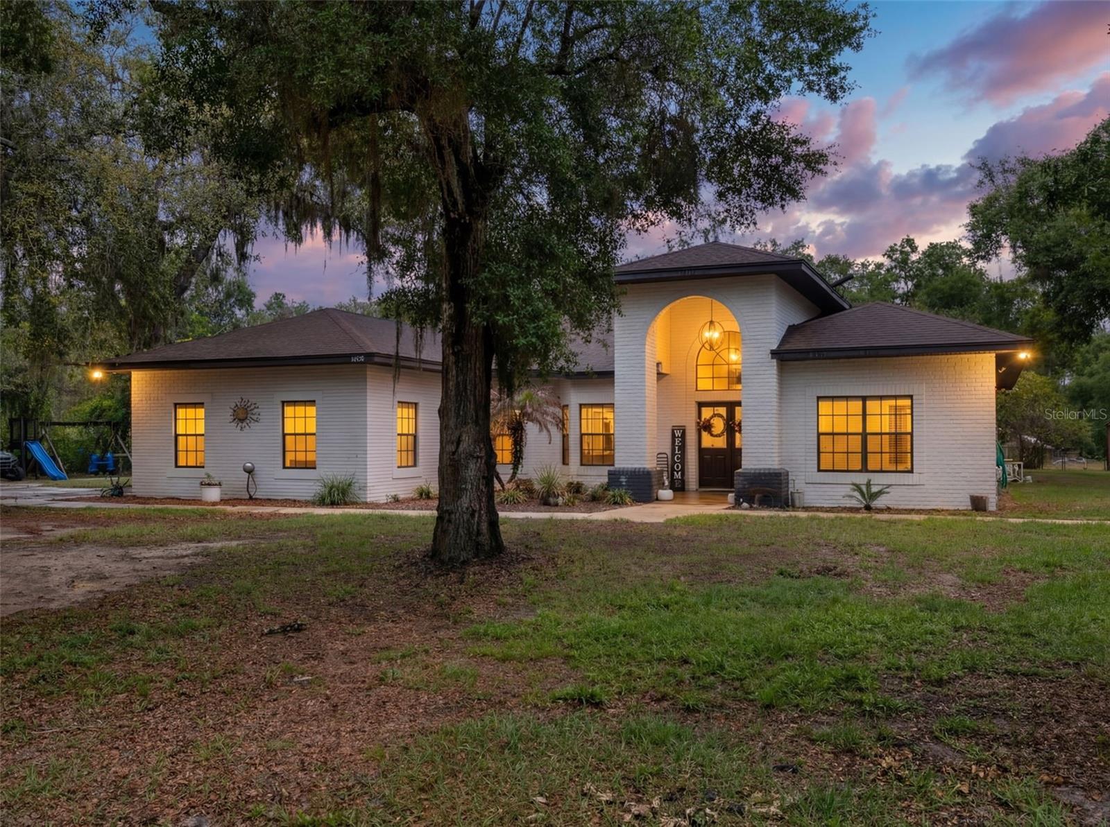 Escape to your own private 10-acre sanctuary at 6030 Millstream Dr in Groveland, where country charm meets modern luxury. This impressive 2,900-plus square foot pool home offers the perfect blend of space and serenity, featuring almost 5 acres high and dry. Outdoor enthusiasts will fall in love with the expansive, screened-in lanai, boasting a sparkling blue pool and ample space for twilight dining, all framed by breathtaking sunset views. The property is a dream for those needing storage or workspace, complete with a massive multi-bay metal barn and workshop perfect for equipment and hobbies.Inside, the heart of the home is a chef-inspired kitchen that will take your breath away. High-end dark cabinetry stretches to the ceiling, perfectly complemented by stunning granite countertops, professional-grade stainless steel appliances, and a unique breakfast bar with rustic wood accents. The living area exudes warmth with exposed ceiling beams, a cozy fireplace, and a striking windmill-style ceiling fan. Retreat to the primary suite, where you’ll find a spa-like bathroom featuring a large soaking tub and a sleek double vanity with marble tops. With four spacious bedrooms, three beautifully updated bathrooms, and a dedicated office space, this home is designed for both comfort and productivity. Whether you are looking for room to roam or a sophisticated space to entertain, this rare Groveland gem offers an unparalleled lifestyle. Experience the peace of rural living without sacrificing the refined finishes you deserve. This property is truly a must-see. New roof in 2022 and many other updates, you need to see this home in person to really appreciate everything about it!