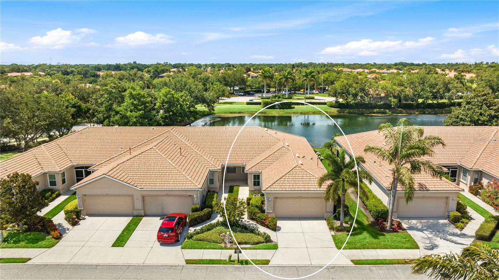 Welcome to a beautifully maintained end-unit villa tucked behind the gates of Lakeridge Falls, where barrel tile roofs, mature palms, and meandering lakeside paths set a relaxed Sarasota tone. Built as part of an intimate four-villa building, this coveted end position wraps the home in extra windows, drawing natural light deep into the living spaces and giving it an airy, sunlit feel. Set on a premium waterfront lot with no rear neighbors, this two-bedroom, two-bath home with a separate den lives larger than its footprint, framing wide, tranquil water views from nearly every main room. Step inside through a private covered entry and the home opens to a bright, flowing layout finished in soft, soothing tones. The great room stretches toward a wall of sliding glass that frames the lake and opens to the covered, screened lanai, the kind of spot made for morning coffee and watching egrets wade along the shoreline. The kitchen sits at the heart of it all, dressed in crisp white shaker cabinetry, quartz counters, a gas range, and a breakfast bar that keeps the cook part of every conversation. A casual dining area and an adjacent den offer flexible room to work, gather, or unwind. Plantation shutters lend a polished, custom feel, while newer luxury vinyl plank flooring warms the bedrooms. The private primary suite faces the water, with its own slider to the lanai, a custom-built walk-in closet system, and a serene bath featuring a double quartz vanity and a roomy walk-in tiled shower. A comfortable guest bedroom and second full bath sit on the opposite side for privacy, and a dedicated interior laundry room with full-size washer and dryer adds everyday ease. With a two-car garage and a true move-in ready feel, this is a home you can simply settle into. Beyond your door, Lakeridge Falls delivers a resort-style lifestyle behind a manned gate. Residents enjoy a grand clubhouse, an expansive heated pool and spa, bocce courts, a sandy lakeside beach with a fire-pit and picnic area, and scenic walking trails that trace the community's lakes. Lawn care and exterior upkeep are handled for you, leaving more time to enjoy it all. The location is just as easy to love, minutes from University Town Center shopping and dining, with downtown Sarasota, St. Armands Circle, and the powdery sand of Lido and Siesta Key beaches a short drive away. Come experience the easy elegance of waterfront living on Florida's Gulf Coast. **THIS PROPERTY QUALIFIES FOR A 1% LENDER INCENTIVE IF USING PREFERRED LENDER. INQUIRE FOR MORE DETAILS.**