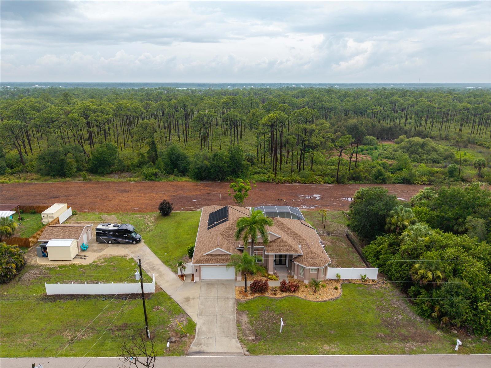 .56-Acre Double Lot | Myakka State Forest Views | Detached Workshop with Mini-Split A/C | Pool & Spa | No HOA| 
Rare opportunity! If you've been searching for space, privacy, and the freedom to park your boat or RV with no HOA restrictions, this Port Charlotte pool home checks all the boxes. Situated on a .56-acre double lot backing directly to the Myakka State Forest, all you have to do is pour your beverage of choice and relax knowing your backyard view is the Myakka State Forest. You can have your garden, pets, and privacy that is incredibly hard to find. 
One of the property's standout features is the detached workshop with its own mini-split A/C system. Whether you envision a hobby space, home gym, ultimate man cave, she shed, or music room, this separate space gives you the freedom to make it your own. 
Inside the home, step through the double glass front doors into the foyer to find formal living and dining rooms, a combined kitchen and family room layout with a casual eat-in kitchen space, 3 bedrooms, 2 bathrooms, and a dedicated office/den (easily a 4th bedroom), plus an oversized primary suite featuring a garden soaking tub and a walk-around shower with dual heads. The interior features crown molding throughout, with tray ceilings highlighting several rooms. 
The screened, heated pool (resurfaced in 2025) features a sun shelf perfect for chilling on those hot Florida days. Just outside the screen enclosure, you can unwind in the standalone spa. Key updates include a new HVAC (2025), a new roof (2022), rain gutters, hurricane shutters. 
This property offers an ideal location close to everyday shopping, local dining, golf courses, I-75, and nearby boat ramps to the Myakka River. You are also an easy drive from the pristine beaches and world-class tarpon fishing of Boca Grande. Best of all, you are just minutes from historic downtown Punta Gorda, famous for its harborfront parks, lively weekend markets, and waterfront dining at Fishermen's Village. It’s the perfect setup—you get all the fun of the town right down the road and total quiet when you come home. Come take a look!