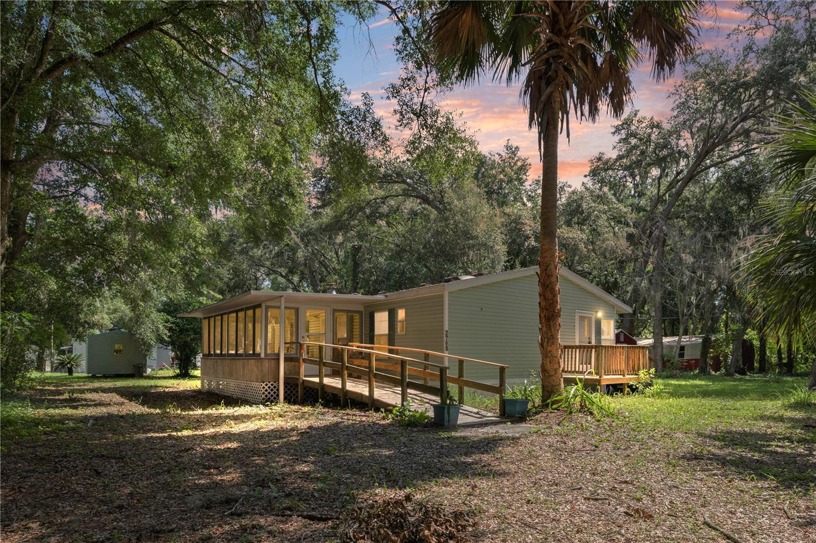 Escape to your own private oasis! Situated on 0.83 acres with private road access, this charming 2-bedroom, 2-bath manufactured home also features a versatile office that could easily serve as a third bedroom. Conveniently located just minutes from The Villages, Florida’s Turnpike, and I-75, you’ll enjoy peaceful living without sacrificing accessibility.

Inside, you’ll love the spacious kitchen, cozy built-in fireplace, and charming cottage-style bump-out dining nook filled with natural light. The fully enclosed patio provides additional living space and includes a built-in ramp for easy accessibility.

Recent updates include a brand-new A/C system with a smart thermostat and a 2016 asphalt roof. Outside, you’ll find a large detached garage with water and electricity, plus a shed with utility hookups, offering plenty of room for storage, hobbies, or a workshop.
If you’re looking for privacy, charm, and convenience all in one property, this is one you won’t want to miss!