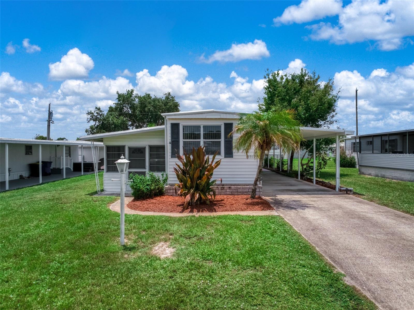 Welcome home to this well-maintained manufactured home offering comfortable living inside and out. The spacious living room flows into the kitchen and dining area, creating a functional layout for everyday living. The home features two bedrooms, a full bathroom with an updated vanity, and attractive wood-look flooring throughout much of the living space. For added peace of mind, the home received an updated metal roof in 2017 and electrical panel was also updated. Enjoy the bright, enclosed Florida room—perfect for relaxing, entertaining, or additional living space. Outside, you’ll appreciate the covered carport with ample parking, a detached storage shed/workshop, and a nicely landscaped, fenced backyard with mature palm trees and plenty of room to enjoy Florida’s outdoor lifestyle. Whether you’re looking for a seasonal retreat or a full-time residence, this home offers great potential and is ready for its next owner. Schedule your private showing today!