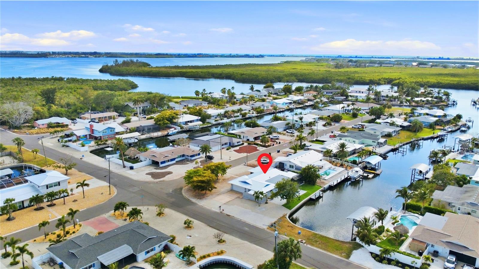 Completely rebuilt from the studs out, 10304 Kingfisher Road W is a fully permitted, canal-front masterpiece in Flamingo Cay, one of Bradenton's most coveted waterfront communities. With 1,781 square feet of meticulously redesigned living space, 3 bedrooms, 2 spa-quality bathrooms, a 2-car garage with side entry, a brand-new pool & spa, and a private dock with canal access, this home delivers the complete Florida waterfront lifestyle with new-construction peace of mind. Every system is new - electrical, plumbing, metal roof, HVAC, & tankless water heater. All permits pulled. Nothing to do but arrive. From the moment you walk in, the design commands attention. Porcelain tile plank flooring flows through every room, signature teal interior doors carry a bold coastal identity, and a sweeping open floor plan connects kitchen, living, and dining seamlessly. Walls of sliding glass frame a direct view of the pool, spa, and sparkling canal beyond. The great room features a dramatic teal shiplap feature wall with custom floating shelves, built-in entertainment center, and a dedicated beverage bar with wine cooler, marble countertops, cedar shiplap backsplash & LED-lit cabinetry - designed equally for quiet evenings in and effortless entertaining.
The kitchen is a genuine chef's showpiece with dual islands - one with a gas cooktop, fluted panel detail & bar seating for four; the second with a prep sink & additional workspace - finished in custom gray shaker cabinetry, thick marble countertops, a professional range hood, open wood shelving & designer teal globe pendants. Under-cabinet lighting, custom tile backsplash & premium appliances complete a kitchen that sets this home apart from anything else in the neighborhood. The primary suite leads to a spa-caliber en-suite with a freestanding soaking tub in its own tiled alcove, a dual rain-head walk-in shower wrapped in floor-to-ceiling designer tile, a double vanity with marble countertops, smart bidet toilet & brushed nickel fixtures. The second full bath matches the same elevated standard - glass-enclosed shower, marble vanity, smart toilet & designer tile throughout. No builder-grade finishes anywhere in this home. Outside, a brand-new pool & heated spa sit center stage on a paver deck within a screened lanai, open to the waterway. A private dock provides direct canal access to Palma Sola Bay & the Gulf - perfect for kayaking, fishing, or a boat day on the water. The two-car garage with side entry & epoxy floors is a genuine rarity in Flamingo Cay, where most homes offer a single car or carport. Add a dedicated laundry room & abundant storage and this home lives larger than its square footage suggests. No HOA and no rental restrictions make this an exceptional income opportunity - similar homes in Flamingo Cay are generating up to $10,000/month during peak summer season as short-term rentals, making this equally compelling as a snowbird retreat or a high-performing investment property. Live in it part of the year, rent it the rest, and let the waterfront do the work for you. Just minutes from the world-class beaches of Anna Maria Island, top waterfront dining & IMG Academy - this is a rare chance to own a fully rebuilt, move-in ready waterfront home, priced to move, in one of Manatee County's most desirable neighborhoods. Whether you're searching for your forever home, a seasonal escape, or a income-producing asset, 10304 Kingfisher Road W delivers on all fronts.