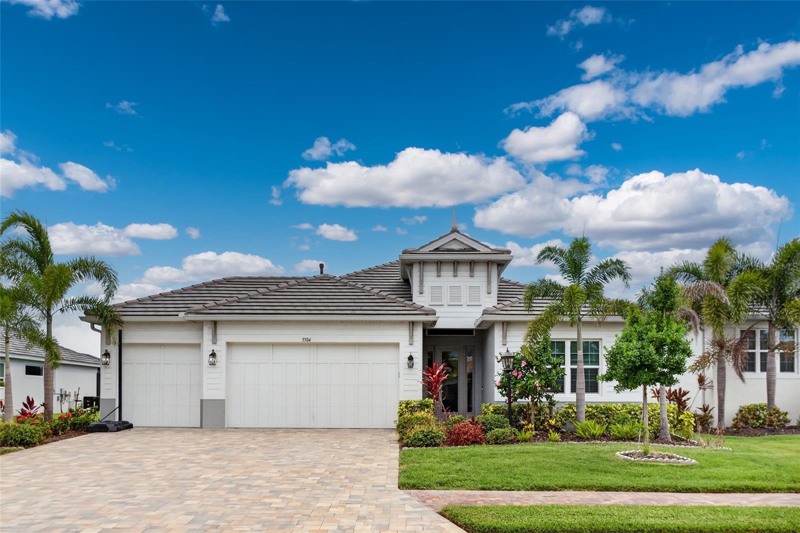 Virtually Staged. RARE NEWER POOL HOME IN A GATED COASTAL COMMUNITY JUST MINUTES FROM IMG ACADEMY. Welcome to 5504 Title Row Drive, a beautifully maintained 2022 Medallion Home in Legends Bay, one of West Bradenton’s most desirable gated communities near IMG Academy, IMG Golf Club, Sarasota Bay, and the Gulf Coast beaches. This 4-bedroom, 3-bath Bermuda plan offers a light, open layout with tile flooring throughout, high ceilings, 8-foot interior doors, impact-rated windows and sliders, a flat tile roof, and a highly functional split-bedroom design with the primary suite privately separated from the guest bedrooms. FEATURE HIGHLIGHTS include a prime location just minutes from the IMG campus, tranquil pond views with the home oriented toward Sarasota Bay, an extended screened lanai, 12-foot pocketing sliding glass doors, a heated saltwater pool with LED color lighting and upgraded pebble-style finish, an upgraded FloCrete-coated lanai/deck, outdoor kitchen rough-in, wide paver driveway, 3-car garage, epoxy-coated garage floor, natural gas service, and security system prewire. The gourmet kitchen is a standout, featuring upgraded 42-inch warm wood-toned cabinetry with crown molding, quartz countertops, a large center island with undermount sink, tile backsplash, under-cabinet lighting, stainless steel appliances, built-in 36-inch gas cooktop, dedicated stainless hood vent, and built-in wall oven/microwave combination. Dovetail cabinetry, full-extension drawers, and soft-close features add quality and function throughout the kitchen and baths. A built-in dry bar with upgraded cabinetry adds extra storage and entertaining appeal. The family room features a tray ceiling with recessed lighting and flows seamlessly to the screened outdoor living area. The primary suite offers three signature accent windows, dual walk-in closets, dual vanities, and an oversized tile-to-ceiling shower. Both secondary bathrooms also feature tile-to-ceiling showers and upgraded finishes, giving the home a cohesive, elevated feel throughout. Legends Bay residents enjoy a gated, maintenance-free setting with community pool, clubhouse, walking paths, scenic lakes, and a pier through the mangroves overlooking Sarasota Bay. Convenient to IMG Academy, IMG Golf Club, SRQ Airport, downtown Sarasota, shopping, dining, Anna Maria Island, Longboat Key, and the beaches, this home offers newer construction, water views, a private pool, and everyday convenience in one exceptional location. A 2-minute cinematic video tour is available online.