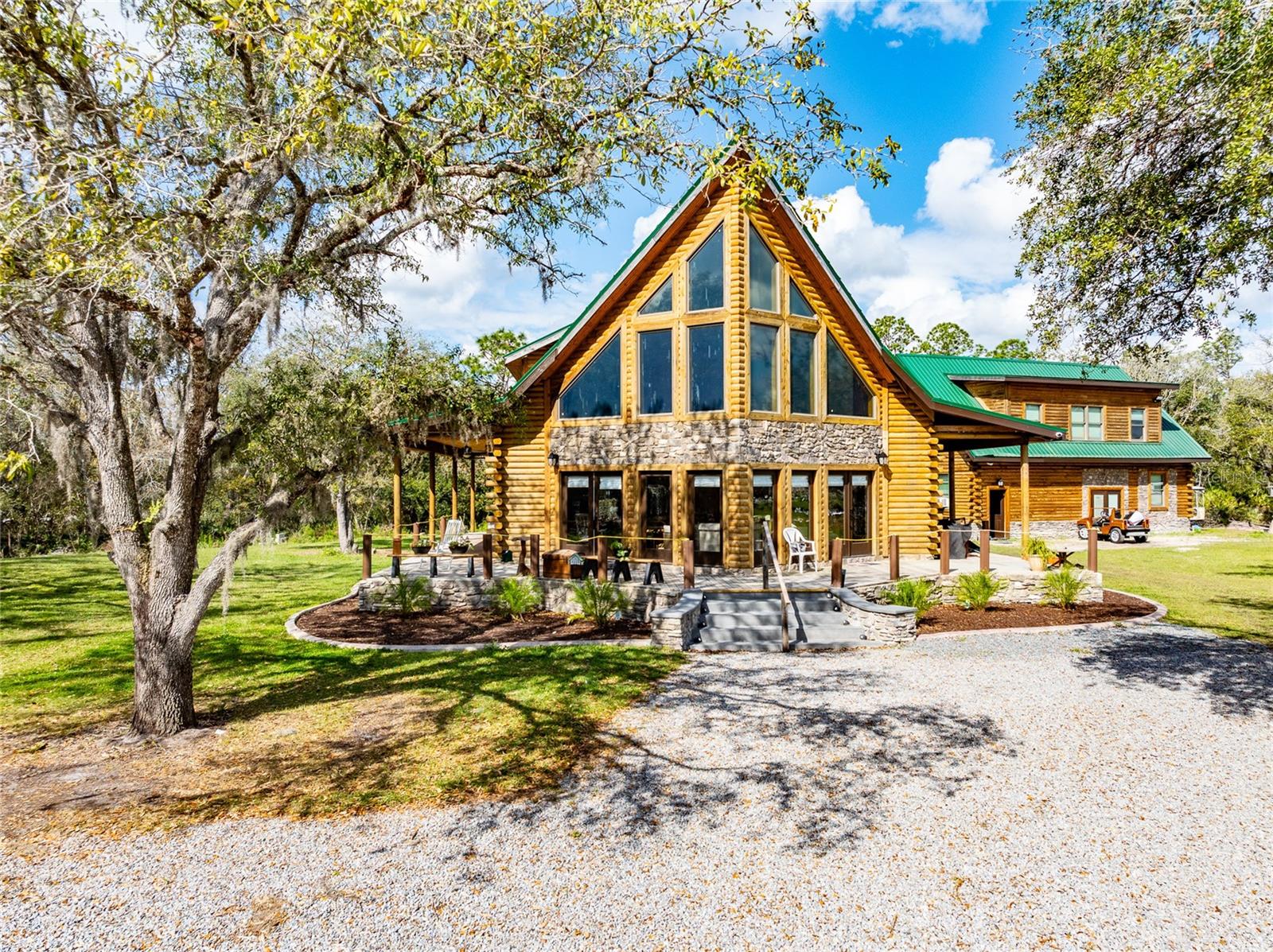 Breathtaking 3-story log cabin on a sprawling countryside estate in a semi-gated community, surrounded by beautiful trees. Seller Financing Negotiable! This home is built with the finest materials & exudes rustic elegance & timeless charm. The rich, hand-hewn logs & stone accents create a warm & inviting exterior, while expansive windows allow natural light to flood the interior. The open-concept features soaring ceilings, gorgeous kitchen, high-end appliances, custom cabinetry, & an island—perfect for entertaining. The primary suite is a peaceful retreat w a spa-like bathroom & private wrap around porch overlooking the trees. Upstairs has 2 bedrooms & loft area for comfort & versatility. There is also a finished third floor of 550 square feet which could be an extra bedroom, storage area, or home office. The 7-acre property boasts 2 ponds that reflect the sky & attract local wildlife, adding to the natural beauty of the land. (Gated, Horse paddock with cover & 2 story carriage house offer endless possibilities.)

A horse paddock is ready for equestrian enthusiasts. Adding to the charm, a stunning 2-story barn (carriage house/mother in law/accessory dwelling/home office/workshop/warehouse) complements the main home, built with the same dedication to craftsmanship. Whether used as a guest house, studio, game room, home office or workshop, this space offers endless possibilities. This estate is a rare blend of luxury & nature, providing a peaceful country lifestyle with modern comforts. The property offers an electric gate and custom pillar entry.