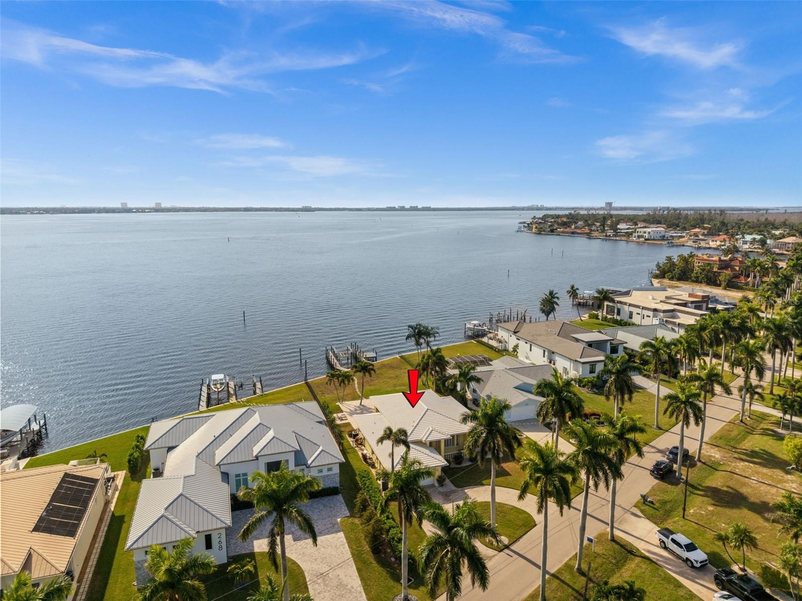 SOUTHERN EXPOSURE RIVERFRONT HOME ON AN OVERSIZED LOT WITH A MULTIMILLION DOLLAR VIEW! Welcome to 264 Bayshore Drive, a rare DIRECT RIVERFRONT property located near Cape Coral’s highly desirable Yacht Club area. Positioned on an oversized lot with approximately 88 feet of Caloosahatchee River frontage and approximately 200 feet of depth, this home offers wide, unobstructed water views, breathtaking sunsets, and direct sailboat Gulf access with no bridges. Southern exposure enhances the outdoor spaces and water views, while a NEW SEAWALL installed after Hurricane Ian adds long-term value and peace of mind. Boaters will appreciate the two docks and boat lift, making this an exceptional waterfront offering. The home features 3 bedrooms, 2 bathrooms, and over 2,200 square feet of living space with soaring ceilings exceeding 12 feet in the living room, dining area, and kitchen. Inside, tile flooring and crown molding run throughout, complemented by a spacious open kitchen with granite countertops and a walk-in pantry. Two sets of pocketing sliding glass doors with full-length transom windows create a seamless indoor-outdoor connection and flood the home with natural light. The primary suite is generously sized with sliding doors to the pool area, two walk-in closets, and a large en-suite bath with dual vanities, a jetted tub, and a separate shower. Outdoors features a heated pool and spa surrounded by a beautiful travertine patio, all overlooking the river. The home does not have a pool cage, allowing for unobstructed views, but is equipped with electric roll-down screens at the rear and accordion shutters for storm protection. Additional features include a tile roof, paver circular driveway, and a quiet street with no through traffic. Offered fully furnished and turnkey, the property is currently part of a successful vacation rental program. Whether enjoyed as-is, continued as an income-producing rental, or envisioned as a future custom riverfront estate, this is a prime opportunity to own one of the most sought-after riverfront locations in Cape Coral.SELLER FINANCING AVAILABLE!