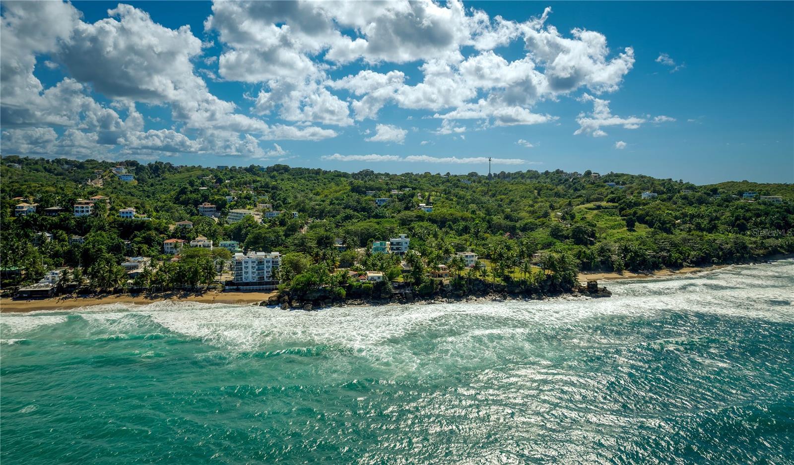 Situated by Sandy Beach in Rincon, this expansive residence enjoys a truly privileged location accented by breathtaking water views. Spanning approx. 7,747.47 Sq. Ft. of total construction, including 2,316 Sq. Ft. of interior living space, the home is perfectly designed for a serene coastal lifestyle or to serve as a premier investment opportunity with two units ideal for short and long-term rentals. Thoughtfully curated for total privacy and comfort, both the first and second floors stand as completely independent sanctuaries with their own kitchens and sun-drenched living areas that connect to spacious north-facing balconies. Each level boasts a dedicated laundry room, in addition to 2 bedrooms and 2 full bathrooms. The property showcases an oversized rooftop overlooking the scenic landscape, as well as a 4-vehicle carport with storage area for added convenience. Recently completed, the residence is also equipped with a water cistern. Rincon is located on the western coast of Puerto Rico. Known as the “Town of Beautiful Sunsets”, the area is renowned for its incredible beaches that serve as an epicenter for watersports such as surfing, diving and kayaking. The region is also home to the Punta Higuera lighthouse and the Rincon Art Walk, which showcases vibrant and one of a kind pieces from emerging artists. Embrace a tranquil lifestyle with picturesque scenery and distinctive atmosphere.