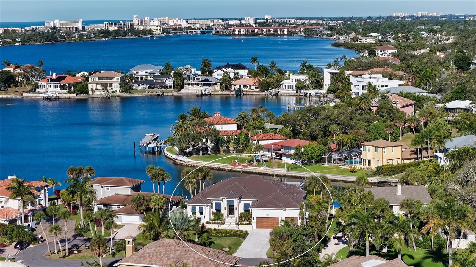 Newer waterfront construction completed in 2023, this elevated contemporary residence offers southern exposure, open design, and direct access to Sarasota Bay in the desirable Southpointe Shores community. Spanning more than 3,000 square feet of air-conditioned living space on one level, the home blends architectural impact with thoughtful functionality and seamless indoor-outdoor living.
Soaring ceilings—some exceeding 14 feet—feature tray and coffered detailing accented by warm wood beams, setting the tone for the expansive great room. A striking stone-clad gas fireplace anchors the space, while walls of impact-rated pocketing sliders open fully to the covered patio and resort-style swimming pool and spa, creating an effortless transition between interior and exterior living.
At the center of the home, the gourmet chef’s kitchen pairs natural wood finishes with refined stone surfaces. Highlights include a statement island with breakfast bar seating, Wolf induction cooktop with pot filler, custom cabinetry with under-cabinet lighting, floating shelves, premium appliances, and a well-appointed butler’s pantry—ideal for entertaining and daily living alike.
The primary suite is privately positioned on the east side of the residence, offering walls of oversized windows and glass sliders that open to the waterfront pool deck. A private spiral staircase leads to a dedicated rooftop terrace with panoramic bay and Intracoastal water views. Inside, the suite features custom a walk-in closet and contemporary en-suite bath designed for relaxation.
Two additional sun-filled guest bedrooms share a beautifully finished bathroom on the west wing, with one bedroom offering a walk-in closet and designer accent wall. A flexible bonus/media room serves as a fourth bedroom, complete with en-suite bath and walk-in closet. Additional features include wood flooring throughout, study/den, a split three-car garage, whole-house generator, tankless water heater, and propane gas service.
Situated on an oversized waterfront lot with approximately 91 feet along the Intracoastal Waterway, this location enjoys cooling bay breezes, open water views, and direct boating access. Southpointe Shores is a quiet cul-de-sac community with convenient proximity to Sarasota’s most sought-after destinations.
Just minutes away are Siesta Key Beach, Crescent Beach, and the Intracoastal marinas. Downtown Sarasota’s cultural offerings—including The Bay Park, Selby Gardens, Van Wezel Performing Arts Hall, galleries, dining, and shopping—are easily accessible, while nearby schools, parks, and everyday conveniences complete the lifestyle. This newly built waterfront home delivers contemporary design, privacy, and location in one exceptional Sarasota setting.
