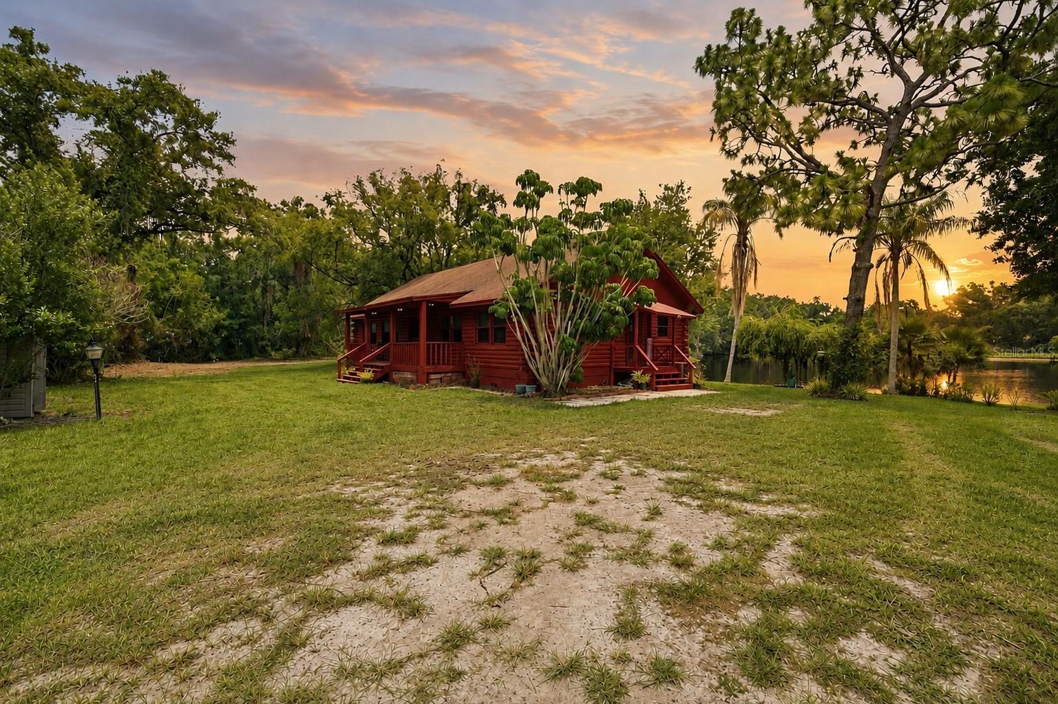 Welcome to 6409 Chiswick Court, a truly one-of-a-kind lakefront property offering 2.23 acres of natural beauty, privacy, and endless possibilities in the highly sought-after Oak Ridge community of New Port Richey. Properties like this rarely come available, combining substantial acreage, over 500 feet of spring-fed lake frontage, existing utilities, and a livable home already in place.

Nestled among mature trees and lush landscaping sits a charming cedar-built cabin featuring 3 bedrooms, 2 bathrooms, and nearly 2,000 square feet under roof when including the expansive front and rear porches. The home offers warmth, character, and a peaceful connection to its natural surroundings. While the cabin could benefit from some cosmetic updates, it provides a comfortable residence, weekend retreat, or potential income-producing rental opportunity.

What truly sets this property apart is its incredible flexibility. Buyers can enjoy the cabin as-is, renovate and preserve its rustic charm, or take advantage of the property's size and buildability to create a custom lakefront estate while living comfortably on-site during construction. With electric service, a private well, and septic system already in place, a future owner may avoid many of the significant expenses and logistical hurdles often associated with developing raw land.

The property features multiple open pasture areas overlooking the lake and is zoned ER (Estate Residential), allowing for grazing animals in accordance with county regulations. The existing pastureland creates an ideal setting for horses and other permitted livestock, offering a rare combination of waterfront living and rural lifestyle potential. Portions of the property are located in desirable X flood zone, providing additional flexibility for future homesite placement.

The spring-fed lake is healthy, scenic, and rich with fish and wildlife, creating a stunning backdrop for everyday living. Wake up to breathtaking sunrises reflecting across the water and enjoy the peace and privacy that only a property of this caliber can provide.

Oak Ridge is an established estate-style community where every home sits on large acreage homesites, yet remains conveniently located near shopping, dining, medical facilities, major roadways, and the Gulf Coast. Whether you're seeking a private waterfront retreat, an equestrian-friendly property, a multi-generational family compound, an investment opportunity, or the perfect location to build your dream estate, 6409 Chiswick Court offers a combination of land, water, existing infrastructure, and future potential that is exceptionally difficult to replicate in today's market.