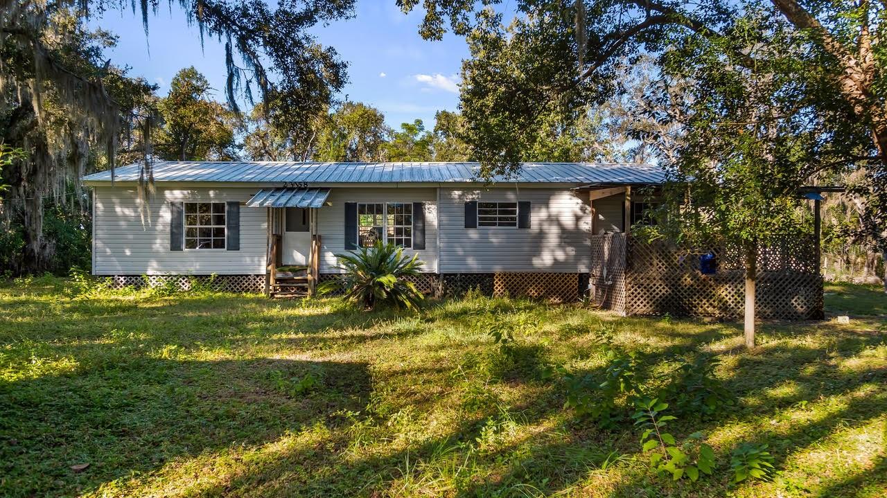 Country Living on 5 Acres – A Groveland Gem with Endless Potential! Dreaming of peaceful country life with space to spread out and make it your own? This 3-bedroom, 2-bath double wide mobile home is nestled on a beautiful 5-acre parcel, offering privacy, nature, and room to grow—just minutes from the Turnpike, shopping, and local dining. Set back from the road and surrounded by mature trees and a small pond, this property is ideal for anyone looking to enjoy the quiet of the countryside without sacrificing convenience. Whether you're imagining a hobby farm, a garden oasis, or a place to keep your animals, this property is ready for your vision. The home features a desirable split floor plan, with a spacious Owner’s Suite that includes a large ensuite bath with dual sinks, a garden tub, and a walk-in shower. Multiple living areas, including a Living Room, Dining Room, and a covered front porch, provide plenty of space to relax and entertain. The kitchen and breakfast nook are ready for everyday living—and offer great potential for future updates. Need room for tools, equipment, or weekend projects? The 16x20 concrete block workshop/barn is a huge bonus, complete with electric and a concrete floor. With no HOA or deed restrictions, you’re free to bring your RV, boat, and animals. Whether you're looking to update and personalize, or simply enjoy the land and location, this property is a rare find. Come see the potential—and picture the future you've been dreaming of!