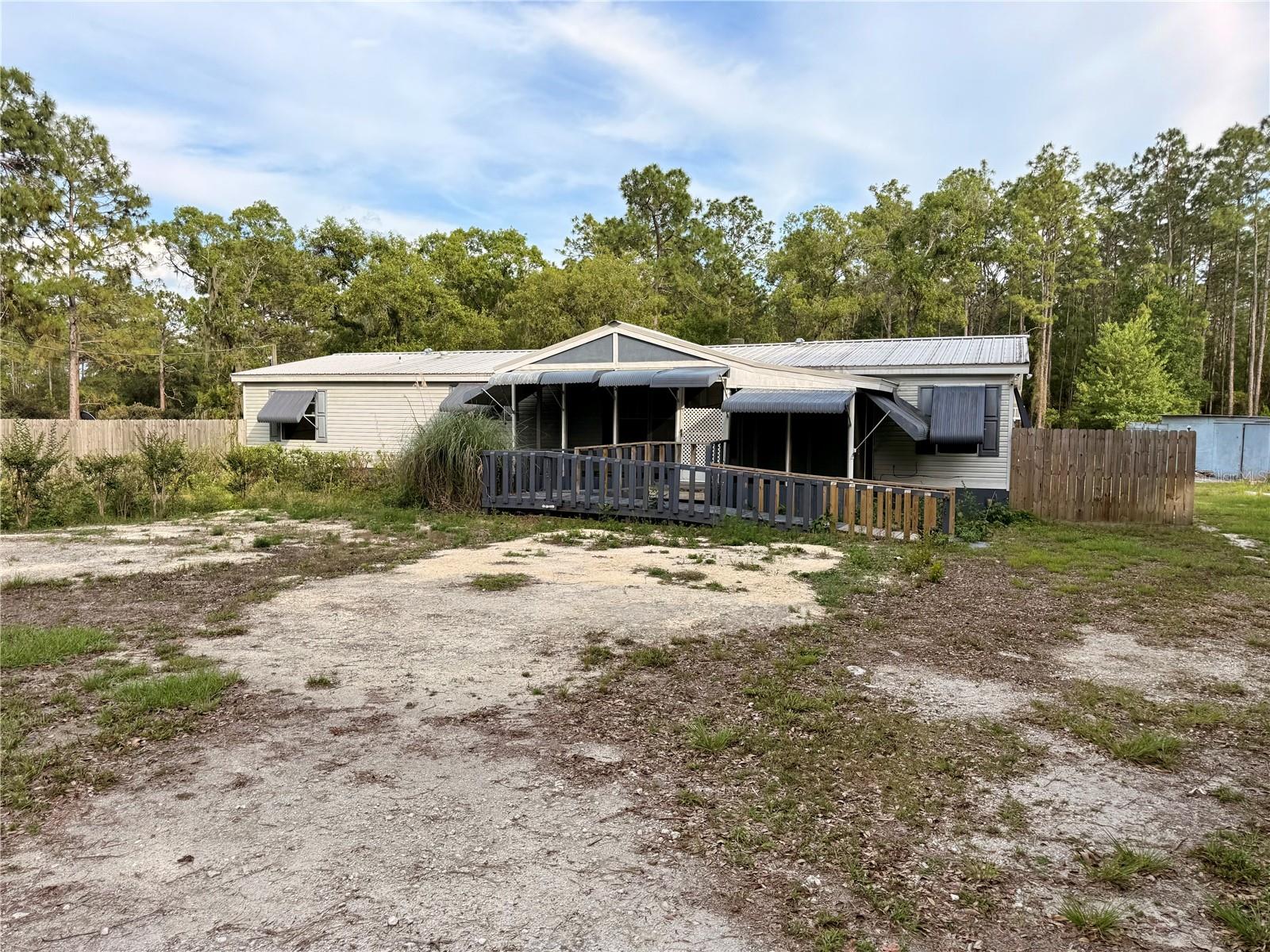 Calling all visionaries, DIY enthusiasts, HGTV binge-watchers, and anyone who’s ever said, “I could totally fix that up.” your opportunity has arrived.This spacious 3-bedroom, 2-bath double-wide offers a generous 1,728 square feet of heated and cooled living space and 2,480 square feet under roof on a beautiful 5-acre parcel in Fox Grove Farms.  Does it need TLC? Let’s just say it’s more “before” than “after” right now—but the potential here is undeniable. Let your vision be your guide.
Inside, you’ll find generously sized bedrooms, large closets, plenty of storage space, and a gas stove because this home is quite literally cooking with gas.Need extra room? Two additional back rooms offer endless possibilities—convert them into additional heated/cooled living space, guest quarters, hobby rooms, a home office, or an in-law setup (because loving your family and wanting your own space can coexist).
Outside is where things really get interesting. The property features multiple outbuildings for storage, workshops, animals, or all the projects you swear you’ll finish someday. They're not exactly Pintrest worthy, but they are undeniably useful! It’s also perimeter fenced, currently with wire fencing that may not win any beauty contests—but hey, it gets the job done.The back portion of the property offers cleared and wooded acreage that could be cleared for additional pasture, recreation space, or expanded mini-farm dreams. Zoned RR Rural Residential/Agricultural, this property is ideal for horses, livestock, gardening, or anyone craving room to roam.Located within riding distance to Goethe State Forest with neighborhood trails, and just a short drive to Black Prong Equestrian Village, the World Equestrian Center, Ocala, Gainesville, Crystal River, the Gulf, and several stunning natural springs.
Bring your tools, your imagination, and elbow grease! Opportunities like this... much land, square footage, and location don’t come around often.