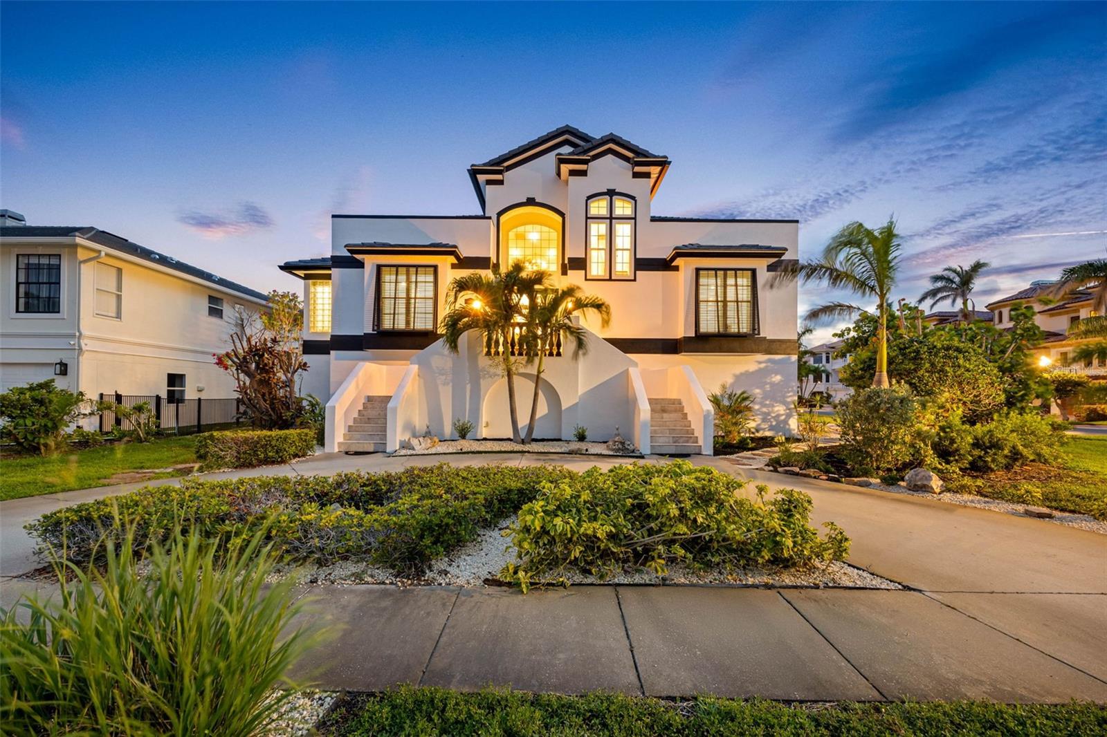 Welcome to 6024 Kipps Colony Drive East, a beautifully updated concrete-block home tucked inside the private gates of Pasadena Yacht & Country Club’s sought-after Kipps Colony. This residence blends comfort, design and thoughtful upgrades in a setting built for everyday living and memorable entertaining. From the curb, a newly installed tile roof and freshly painted exterior signal the care and investment poured into the home. Step inside, and you’re greeted by a sunlit great room with soaring 20-foot ceilings, gleaming marble floors and full-length French doors that open to the terrace, ideal for seamless indoor-outdoor living. A dramatic double-sided fireplace adds warmth and architectural interest, setting the tone for relaxed elegance. The remodeled kitchen is built for the way we live now, offering clean lines, functional storage and refined finishes. Custom soft-close cabinetry, quartz countertops, and Bosch stainless steel appliances are accented by brass fixtures and designer lighting that bring the space together with a quiet sense of luxury. Retreat to the primary suite, where a private fireplace, built-in morning bar and dual spa-inspired baths create a personal escape. One bath is light and serene, with a freestanding soaking tub, artisan tilework and soft blue cabinetry. The other is tailored and warm, with rich wood, marble finishes and striking lighting. Two walk-in closets and direct laundry access keep your daily routine effortless. Upstairs, two generous guest suites each offer private baths, walk-in closets, and hardwood floors. French doors lead out to balconies where you can enjoy breezes and water views, ideal for reading, unwinding or hosting overnight guests. Out back, a wide 40-by- 38-foot terrace provides room for grilling, lounging or future plans for a custom pool. A second laundry area, conveniently just off the garage, makes outdoor living even easier—ideal for managing towels and gear once the pool is installed. With no rear neighbors, the space is quiet, private and ready for your vision. The four-car garage has extra depth and storage—ideal for a home gym, workshop or collector’s setup. Additional highlights include plantation shutters, detailed millwork, hurricane protection, and adjustable ambient lighting to match the mood or time of day. As a resident of Pasadena Yacht & Country Club, you’ll have access to optional membership amenities including a deepwater marina, 18-hole golf course, tennis courts, a resort-style pool and a full-service clubhouse. All of this, just minutes from Gulf beaches, local dining, and downtown St. Petersburg’s vibrant arts and culture.