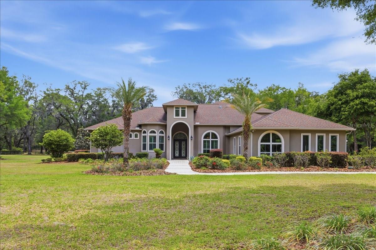 Situated on 5 acres in the gated community of Santa Fe Forest, this 5,087 square foot residence offers a combination of scale, design, and outdoor living. The interior is defined by soaring ceilings, including a dramatic 22-foot main living area filled with natural light. The layout provides expansive living and dining spaces with an open flow into the kitchen, featuring ample cabinetry, stone countertops, a large island workspace, and built-in appliances. The home includes 5 bedrooms and 5 full bathrooms along with a half bath. One of the bedrooms offers private exterior access and an en-suite half bath, providing flexibility for a variety of uses. The primary suite features dual custom walk-in closets with built-in shelving and storage, along with an en-suite bath complete with a walk-in shower, soaking tub, and dual vanities.

Outdoor living is centered around a resort-style pool and spa, surrounded by an extended paver deck and a covered lanai with a wood-paneled ceiling, summer kitchen, and fireplace. Additional features include three fireplaces located in the primary bedroom, family room, and lanai, a four-car garage, irrigation system, and multiple flexible living areas. Built in 2017, the home offers modern construction and systems and has been refreshed with updated interior lighting throughout.
