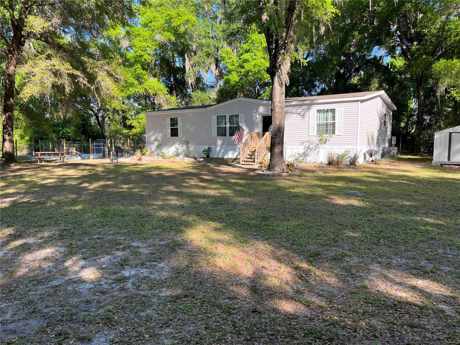 This exceptional 4.5-ACRE property offers the perfect blend of modern amenities, privacy and tranquil country living. Within half a mile from the Public Boat Ramp at Santa Fe Lake, this charming mobile home, built in 2021, features three spacious bedrooms and two full baths designed with comfort and style in mind. You’ll enjoy peace of mind with a new well installed in Dec 2025, ensuring a reliable water source for your family.

The entire property is securely enclosed with no-climb fencing, providing safety for pets and children while maintaining the beauty of the natural surroundings. An additional fencing around the mobile home creating a yard with more security and privacy. A convenient 12x20 carport with pavers offers protection for your vehicles, and a sturdy 8x10 shed provides ample storage for tools and outdoor equipment. Additionally, a 20x20 concrete pad is perfect for entertaining or meeting your storage needs.

With a the septic system installed in 2021, you can trust in efficient waste management for years to come. The home features an AC unit equipped with a 10-year warranty, promising you cool comfort throughout the Florida summers. The property also boasts many fruit producing citrus trees. This property is a true gem, ideal for those seeking a peaceful lifestyle while still enjoying modern conveniences. Don’t miss your chance to own this slice of paradise in Melrose! Schedule a tour today and envision your future in this idyllic setting.