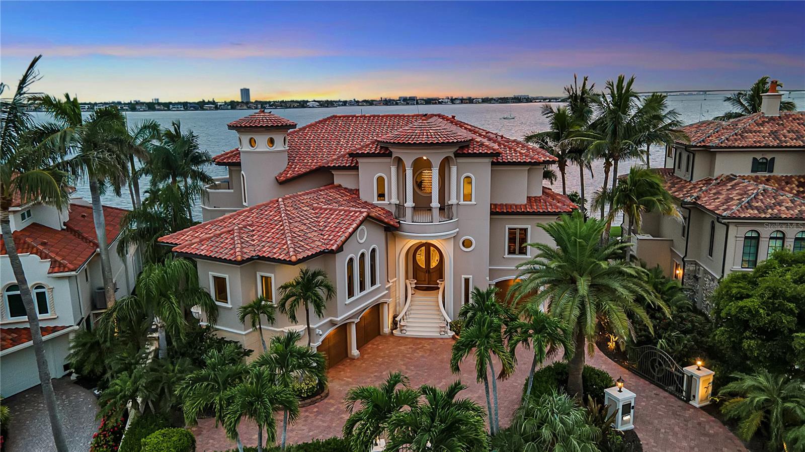 This immaculate Sarasota Bay front estate is prominently positioned on the point of Harbor Drive.  It embodies the pinnacle of luxury waterfront living, where timeless architecture, exceptional craftsmanship, and breathtaking panoramic water views converge in one of Sarasota's most prestigious bayfront neighborhoods. Showcasing hurricane-impact windows and doors throughout, this meticulously maintained residence offers exceptional storm protection, energy efficiency, and peace of mind, further complemented by a one-year-old roof and a whole-house generator. Designed to maximize its extraordinary setting, the home features five outdoor terraces with sweeping views of Sarasota Bay, the Ringling Bridge, downtown Sarasota, Big Pass, and the Gulf of Mexico. Inside, the beautifully renovated interior strikes the perfect balance between elegance and comfort. The chef's kitchen, primary bath, and powder room have been thoughtfully remodeled, while timeless finishes include Italian porcelain tile flooring, five fireplaces, custom millwork, intricate built-ins, designer ceiling treatments, crystal chandeliers, integrated music systems, security cameras, and a comprehensive alarm system. The thoughtfully designed floor plan includes a custom bar, climate-controlled wine storage, a chef's kitchen with walk-in pantry overlooking the family room, a private office, theatre room, and separate primary and guest living levels, all connected by a convenient four-stop elevator. Designed for effortless indoor-outdoor living, the residence offers an exceptional collection of entertaining spaces, including a summer kitchen, multiple outdoor dining areas, a fire pit, open sun deck, infinity-edge pool, and spa—all perfectly positioned to capture Sarasota's spectacular sunsets over the bay. Boating enthusiasts will appreciate the property's unobstructed, deep-water access to Sarasota Bay and the Gulf of Mexico. The private dock is equipped with security sensors, underwater Snook lighting, a 24,000-pound boat lift, an additional 14,000-pound lift, and a 7,000-pound lift currently configured for kayaks or jet skis, providing remarkable flexibility for multiple watercraft. Offering the rare combination of hurricane-impact windows and doors throughout, recent major improvements, resort-inspired outdoor living, deep-water boating access, and an unrivaled Harbor Acres location, this exceptional waterfront estate is just minutes from downtown Sarasota, Southside Village, Siesta Key, and the area's world-renowned Gulf beaches.