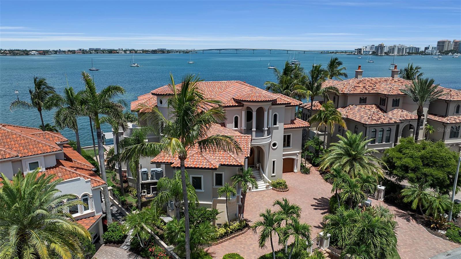 This immaculate Sarasota Bay front estate is prominently positioned on the point of Harbor Drive.  It embodies the pinnacle of luxury waterfront living, where timeless architecture, exceptional craftsmanship, and breathtaking panoramic water views converge in one of Sarasota's most prestigious bayfront neighborhoods. Showcasing hurricane-impact windows and doors throughout, this meticulously maintained residence offers exceptional storm protection, energy efficiency, and peace of mind, further complemented by a one-year-old roof and a whole-house generator. Designed to maximize its extraordinary setting, the home features five outdoor terraces with sweeping views of Sarasota Bay, the Ringling Bridge, downtown Sarasota, Big Pass, and the Gulf of Mexico. Inside, the beautifully renovated interior strikes the perfect balance between elegance and comfort. The chef's kitchen, primary bath, and powder room have been thoughtfully remodeled, while timeless finishes include Italian porcelain tile flooring, five fireplaces, custom millwork, intricate built-ins, designer ceiling treatments, crystal chandeliers, integrated music systems, security cameras, and a comprehensive alarm system. The thoughtfully designed floor plan includes a custom bar, climate-controlled wine storage, a chef's kitchen with walk-in pantry overlooking the family room, a private office, theatre room, and separate primary and guest living levels, all connected by a convenient four-stop elevator. Designed for effortless indoor-outdoor living, the residence offers an exceptional collection of entertaining spaces, including a summer kitchen, multiple outdoor dining areas, a fire pit, open sun deck, infinity-edge pool, and spa—all perfectly positioned to capture Sarasota's spectacular sunsets over the bay. Boating enthusiasts will appreciate the property's unobstructed, deep-water access to Sarasota Bay and the Gulf of Mexico. The private dock is equipped with security sensors, underwater Snook lighting, a 24,000-pound boat lift, an additional 14,000-pound lift, and a 7,000-pound lift currently configured for kayaks or jet skis, providing remarkable flexibility for multiple watercraft. Offering the rare combination of hurricane-impact windows and doors throughout, recent major improvements, resort-inspired outdoor living, deep-water boating access, and an unrivaled Harbor Acres location, this exceptional waterfront estate is just minutes from downtown Sarasota, Southside Village, Siesta Key, and the area's world-renowned Gulf beaches.