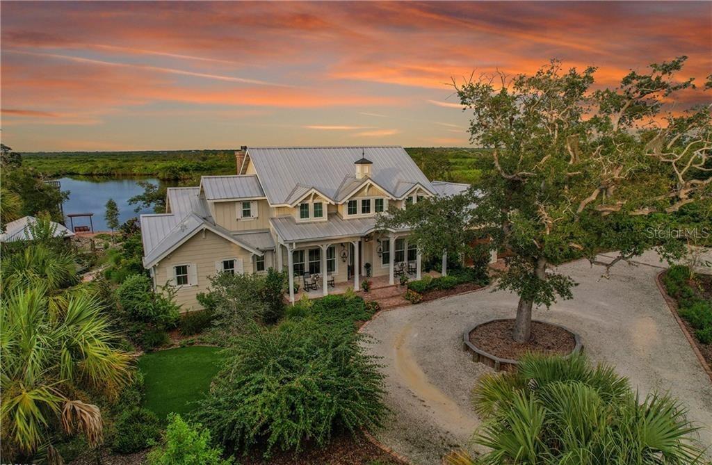 This private, gated, meticulously designed, old Florida style home, located on a 4.5 acre preserve, represents an exceptional opportunity for discerning buyers. Spanning 5,500 square feet under roof and 3,300 square feet under air, this property provides ample space for both indoor and outdoor relaxation and entertaining. The entrance foyer welcomes you with its elegant antique barn style door and vaulted ceilings, leading into a living room adorned with natural light from skylights and 3 sets of double French doors. The soaring handmade brick gas fireplace draws you into the living room. The spacious kitchen is equipped with stainless steel appliances, an over-sized butcher block island with a sink, and a breakfast bar, ensuring a seamless flow for culinary enthusiasts and social gatherings. The dining area, featuring tasteful wainscoting, further enhances the home’s refined aesthetic. All bedrooms feature en suite bathrooms and walk-in closets. An upstairs bedroom boasts a gorgeous HGTV inspired tailor made bunk room with two queen and two full size beds. Amongst the books in the library you'll find a customized murphy bed and in the den you'll find the tv hidden behind handcrafted wooden doors. The home also has an eye for the practical with both indoor and garage holiday storage closets. No space is left unaccounted for with wall to wall cabinets in the garage with its squeaky clean epoxy floor. The home has a generous 1,000 gallon propane tank to support the whole house generator and you can feel safe with hurricane impact windows and doors. The standing seam metal roof offers superior weather protection. Outdoor living is at its finest with a screened in living room and outdoor kitchen, gas fireplace, and pool, all set against the backdrop of tranquil views of Deep Creek. With over 300ft feet on the waterfront, it's a short boat ride to the Peace River and then out into the Gulf. The metal roof boat house, with 10,000 lb boat lift, accommodates up to a 30 foot boat surrounded by a composite material dock with a fish cleaning table for your catch of the day. This property not only offers luxurious amenities but also a lifestyle enriched with the proximity to local parks, recreational facilities, and waterfront activities. This residence is a must-see for those seeking stunning water views and lush landscaping in their own private oasis.