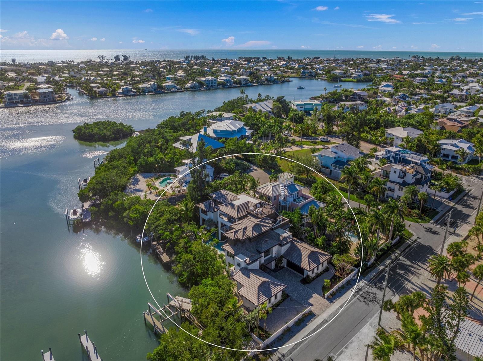 A rare expression of modern island luxury, this newly constructed Polynesian-inspired estate is ideally positioned on South Bay Boulevard in Anna Maria, offering privacy, architectural distinction, and sweeping bay views. Thoughtfully designed around a private, lush interior courtyard, the home centers on a resort-style pool and spa that seamlessly connect to covered outdoor living areas, creating a true indoor-outdoor lifestyle.

The residence offers 5 bedrooms, 6 bathrooms, and expansive living spaces defined by clean architectural lines, warm wood accents, and walls of glass that frame tranquil water and tropical landscape views. The open main living level is ideal for entertaining at scale, anchored by a chef’s kitchen featuring custom cabinetry, a full walk-in pantry, and an oversized island, complemented by generous dining and gathering spaces that open directly to the pool courtyard.

The primary suite is a private retreat, offering a custom-designed walk-in closet with a dedicated laundry area and a spa-inspired bath with a soaking tub positioned before picture windows overlooking the bay. A dramatic indoor-outdoor shower further enhances the immersive waterfront experience.

Outdoor living is elevated with multiple covered terraces, a tranquil spa beneath a living green ceiling, and an expansive rooftop deck showcasing panoramic water views—perfect for sunset enjoyment and evening entertaining. Additional highlights include an elevator servicing all levels, premium finishes throughout, and thoughtfully designed spaces that balance luxury with everyday livability.

Located just moments from Anna Maria’s renowned beaches, dining, and shopping, this exceptional residence presents a rare opportunity to own a newly built architectural masterpiece on the bay.