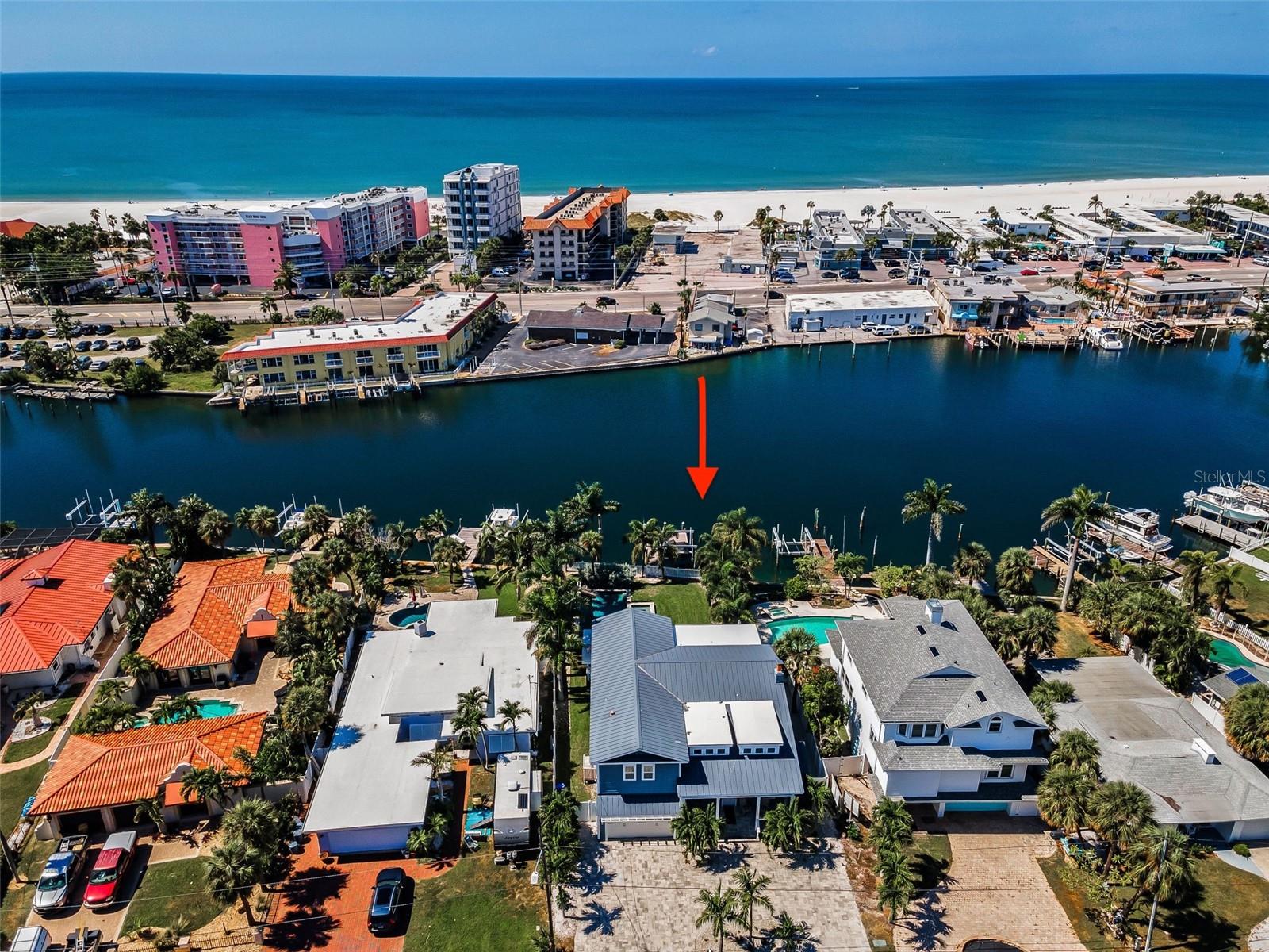 Welcome to a modern coastal masterpiece where luxury, craftsmanship, and design converge in the heart of St. Pete Beach. Taken down to a few exterior walls and rebuilt in 2018 by CASK Construction, this 4 bedroom, 4 bathroom extraordinary residence exudes sophistication from the moment you arrive. A beautifully paved circular driveway framed by lush palms sets the tone for what awaits beyond the front door. Inside, the open-concept floor plan unfolds across porcelain tile floors, with captivating water views and designer details at every turn. The living room, anchored by a cozy wood-burning fireplace, flows seamlessly into the expansive family room, both accented by custom coffered ceilings that elevate the space. The chef’s kitchen is a showstopper, featuring Carrera marble backsplash, Carrera quartz countertops, and an oversized island with seating for eight. Solid wood shaker cabinetry, dual ovens, two full-size refrigerators, a walk-in pantry, and a dedicated wet bar make entertaining effortless. The first level also includes a spacious en-suite guest room, a full pool bath, and a well-appointed laundry room with ample storage. A striking staircase with sleek cable railing leads upstairs, where high-end engineered wood floors guide you to a master suite that redefines luxury. Spanning 1,100 square feet, the primary retreat offers 10-foot ceilings, balcony access for sunset views, a freestanding tub, a double-entry marble shower with five shower heads, dual vanities with makeup counter, his-and-hers toilets, and two grand walk-in closets. Each guest suite upstairs is equally refined, with vaulted ceilings and balcony access. Plantation shutters, crown molding, and smooth wall finishes add elegance throughout. Outside, your private waterfront oasis awaits, complete with a Trex deck, built-in BBQ with granite countertops, and bar seating overlooking a sparkling and heated PebbleTec saltwater pool and spa. The dock, built in 2018, includes a 7,000-lb lift, deep sailboat water, and shore power for larger vessels, all set along a newer seawall with direct Gulf access. Manatees and dolphins are frequent visitors to this serene backdrop, and the home’s premier location allows you to walk to the beach, restaurants, and the iconic Don Cesar, with easy access to downtown St. Pete and Tampa International Airport. Every inch of this residence embodies refined coastal living at its absolute finest. Dimensions are estimates, buyer to verify dimensions.