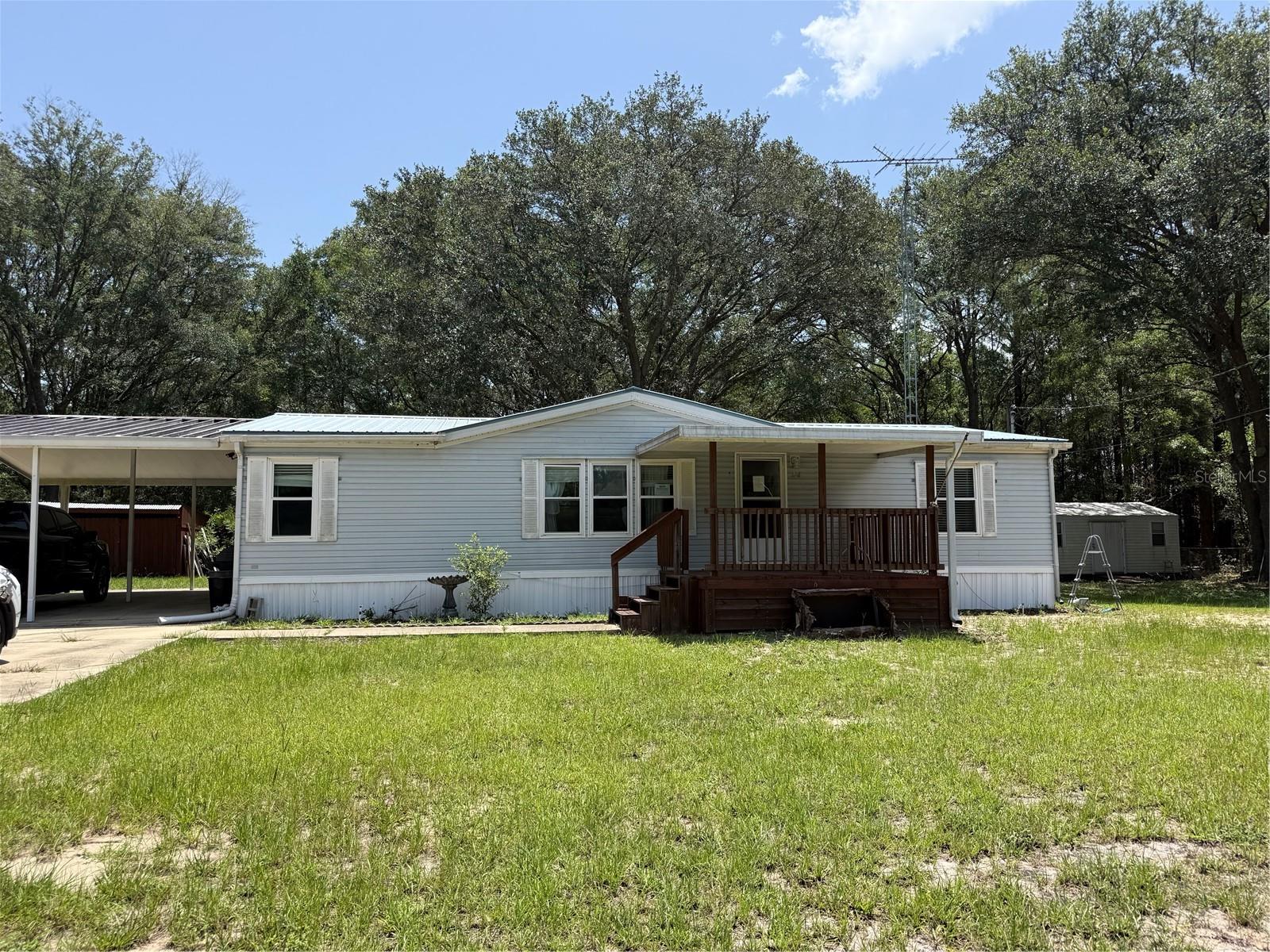 INVESTORS Tucked away on a secluded lot in Interlachen, this 3-bedroom, 2-bath modular home offers the kind of privacy that’s getting harder to find. Just under half an acre, fully fenced, and set back from the noise.  Bring your boat and enjoy the outdoor living. Close to Lake Grandin and numerous other lakes. Short drive to the St. Johns River. 
The large front porch is made for morning coffee and watching nothing in particular happen. Out back, an oversized screened porch extends your living space into the Florida evenings — bug-free, breezy, and ready for whatever you want to make of it. A covered carport keeps your vehicle out of the sun, and the fenced yard gives pets, and gardens room to roam.
Inside, a functional three-bedroom, two-bath layout keeps things comfortable and low-maintenance.
Whether you’re looking for a quiet primary residence, a weekend retreat, or an affordable entry into Putnam County living, 726 Guy Ave delivers space, seclusion, and simplicity. This property is a short drive to Gainesville, Palatka and Jacksonville. 
This property has an investor incentive see the realtor remarks.