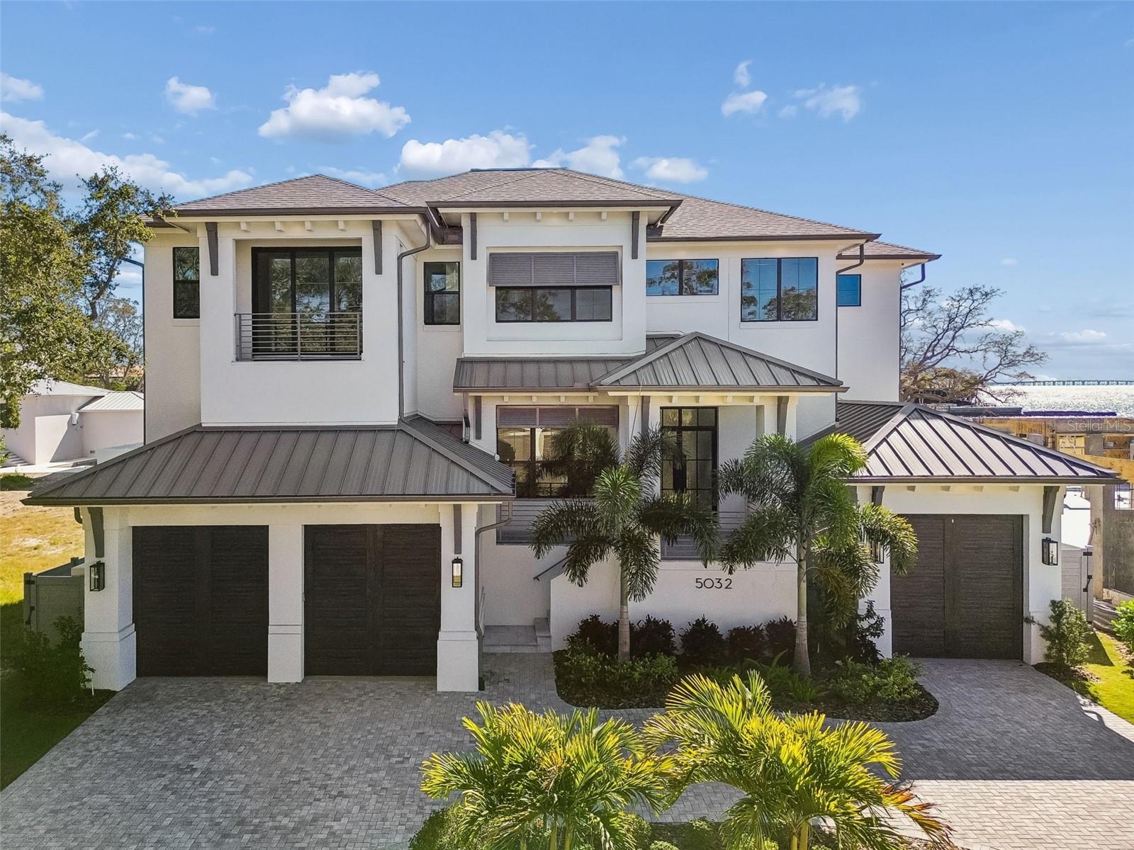 Welcome to the custom “St. Lucia” by Taralon Homes, located in South Tampa’s Beach Park neighborhood. This 5 bedroom, 6 full baths, and 2 half baths modern coastal home features a clean architectural profile with impact-rated black-frame windows, beautiful ceiling details, sand-finish stucco, and metal roof accents.

A grand two-story foyer leads into the formal dining room and expansive living room with a 60" linear gas fireplace. The fabulous chef’s kitchen includes Thermador appliances, bone tile backsplash, dual farm sinks, an oversized island, pot filler, ice machine, custom maple cabinetry to the ceiling and overlooks the family room with a gas fireplace. Wide retractable corner sliders open the entire room to the lanai, capturing water views and seamlessly expanding the main living area outdoors.  The first floor also offers a guest suite with an ensuite bathroom, pool bath, and a large laundry utility room which can be converted to a back kitchen.

Upstairs features a generous game room with balcony access, two secondary suites, and a second laundry room. The master bedroom includes tiered ceilings, dual walk-in closets by ClosetArt, and a spa-style bath with Brizo Invari fixtures, double vanities, a large walk-in shower, and a freestanding soaking tub.

Outdoor living showcases a large covered lanai with Synergy pine ceilings, an outdoor gas fireplace, and a full outdoor kitchen with Alfresco grill, Versa burner, exhaust hood, refrigerator, and stone counters. A resort-style infinity pool and spa with travertine decking enhance the setting.

Additional features include a Scranton elevator serving all floors, 3-car garage with epoxy flooring, central vacuum, custom aluminum railings, an upper cabana roof deck, and a fully landscaped oversized lot.

Located minutes from Tampa International Airport, International Plaza, Soho, Hyde Park Village, top-rated schools, and Tampa’s best dining. Buyer to verify all measurements and details.