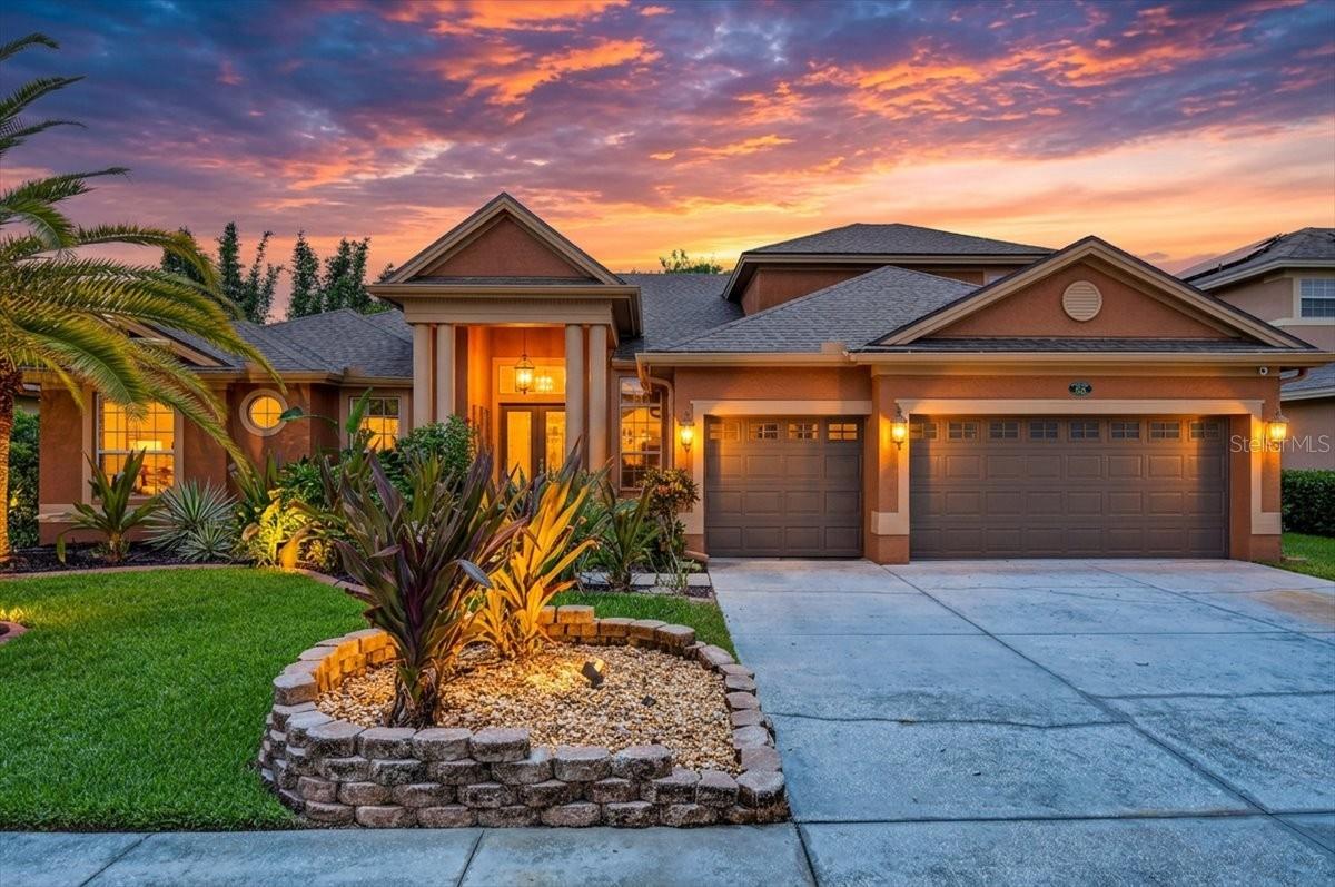 Some homes are built to impress. Others are designed to be lived in and loved. At 16410 Ivy Lake Drive, you don't have to choose. Behind the gates of Ivy Lake Estates, a lush tropical walkway leads to a custom waterfall wall where the gentle sound of cascading water welcomes you home, creating a resort-like arrival unlike anything else in the neighborhood. It's a fitting introduction to this beautifully updated 5-bedroom, 3-bath executive pool home with a 3-car garage, offering more than 3,500 square feet of thoughtfully designed living space. Inside, soaring 11'+ ceilings and an open, light-filled layout create an immediate sense of grandeur. Tray ceilings, crown molding, fresh interior paint, updated lighting, and newer laminate and luxury vinyl plank flooring (2023/2024) blend timeless architecture with modern style, while a new roof (2021) provides peace of mind. Designed for both everyday living and entertaining, the thoughtfully designed split-bedroom floor plan offers four bedrooms plus a dedicated executive office on the main level, creating privacy for family and guests alike. Upstairs, a private fifth bedroom and spacious bonus living area provide endless flexibility as a home theater, game room, guest retreat, fitness studio, or multigenerational living space. The kitchen is both elegant and functional, featuring granite countertops, stainless steel appliances, a gas range, a large island with prep sink, breakfast bar seating, new pendant and under-cabinet lighting, and custom wood pantry shelving that adds beauty and organization. The adjoining family room and sliding glass doors create a seamless connection to the outdoor living spaces. The primary suite is a peaceful retreat with its own tray ceiling, generous sitting area, and spa-inspired bath complete with dual vanities, a walk-in shower, and a column-framed garden tub beneath a sunlit window. Outside, the tropical setting truly shines. A screened lanai surrounds the sparkling pool, enhanced by a brand new pool heater (2025), while the protected conservation backdrop creates an exceptional sense of privacy and openness. The uninterrupted natural views beyond the rear property line make the outdoor living space feel remarkably expansive, creating your own private Florida retreat. Located in one of Odessa's premier gated communities with low HOA fees and no CDD, residents enjoy a neighborhood park, playground, soccer field, basketball court, and volleyball court just a short walk away, along with convenient access to State Road 54, the Veterans Expressway, top-rated schools, shopping, dining, and Tampa International Airport. This is more than a beautiful home—it's a place where everyday life feels like a getaway.