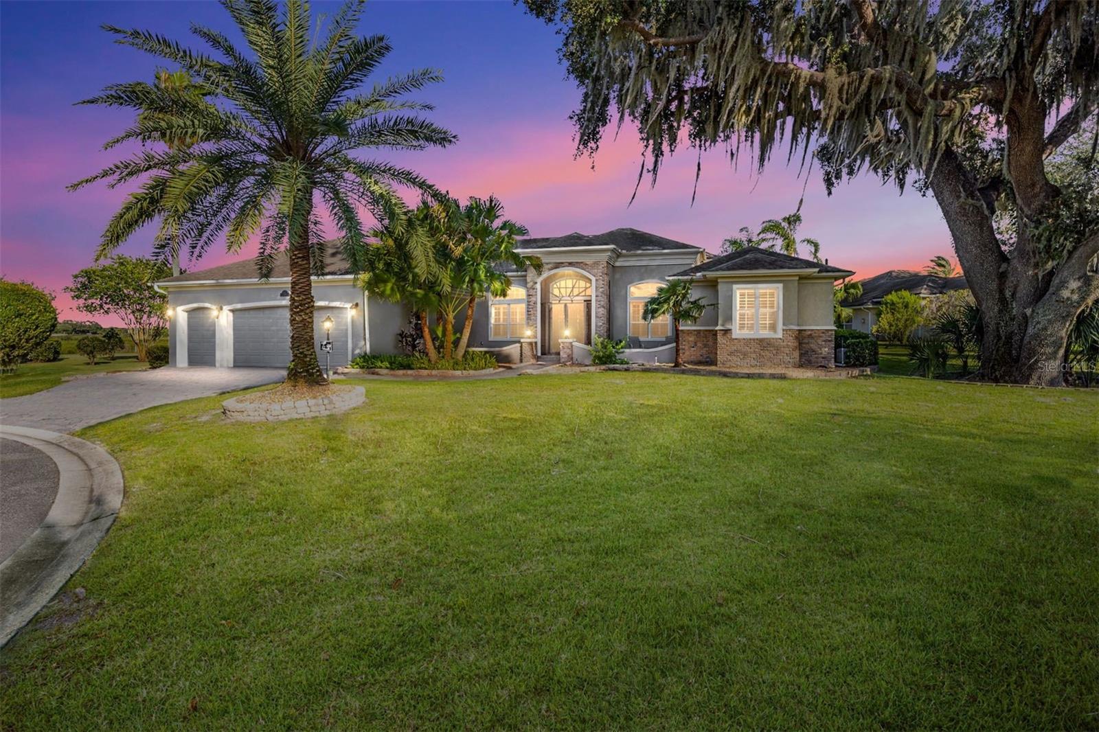 ICONIC, STUNNING, UNIQUE and ONE-OF-A-KIND only begin to describe this expanded St. James Premier home with over 5400 SF of air conditioned living space with 5 bedrooms and 4 ½ baths.  The oversized ¾ acre lot is located directly on Lake Sumter in the prestigious Village of Bridgeport at Lake Sumter.  Enjoy the convenience of a 5-minute golf cart ride to Lake Sumter Landing or the practice facilities at Palmer Legends Golf Course.  Take in the panoramic views of Lake Sumter and the 6th & 7th holes of the Riley Grove Golf Course at Palmer Legends. There are three master suites and each has elegant en-suite baths with Roman Showers, granite counters and large walk-in closets.  The two-story Atrium, with floor-to-ceiling windows and a magnificent Italian Quartz wall sculpture, has a beautiful red oak staircase leading to an upstairs Master Suite, Office, or Art Studio, you decide. This suite has incredible views of Lake Sumter and a screened balcony. 
The family room has floor-to-ceiling sliding glass doors that open to a massive lanai and pool area.  Audio and energy saving LED lighting have been added throughout the main living areas and the lanai.  Updated light fixtures and ceiling fans contribute to the soft contemporary style.  Six TV’s and 3 surround sound systems are included with the home.  The covered lanai is a perfect entertainment area for large or small gatherings at over 750 square feet and includes a built-in summer kitchen featuring granite counters and backsplash, a Twin Eagles grill, Kamado Joe smoker, wet bar with refrigerator, and commercial icemaker with a rated capacity of 240 pounds of ice per day. Breathtaking views highlight the solar and gas-heated spa and pool with 3 waterfalls.  The gourmet kitchen features updated Kitchen Aide, Miele and Cafe stainless steel appliances, granite counters, a gas range with baking drawer, microwave with air fryer and convection capabilities and a closet pantry. This home will exceed your expectations for both entertaining and living. Two additional downstairs bedrooms share a Jack & Jill bath with granite counters.  The flooring is Italian porcelain tile and engineered, scraped hardwood throughout. Window treatments are all plantation shutters.  Crown molding everywhere even including the lanai.  Twelve-foot ceilings create an open and spacious feel. There is a whole home water softener, lightning rod protection, brand new roof and huge amounts of built in storage space in the garage.  With well over 5,000 sq. ft. of air-conditioned living space and massive outdoor living areas, this magnificent home is unlike anything else in The Villages. It can be yours but don’t wait. Make your appointment for a private tour today. (Bond Payoff $17,864.46; Annual Bond payment $1,830.74; Annual Bond Maintenance $1,122,37.)