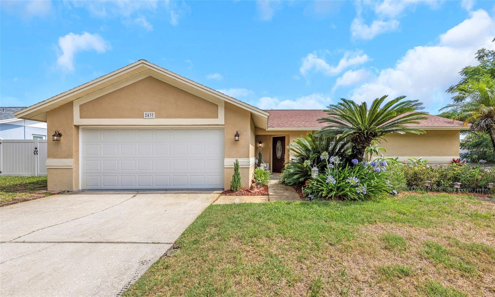 Nestled on a beautifully landscaped oversized corner lot, this meticulously maintained 3-bedroom, 2-bathroom home offers the perfect blend of comfort, style, and Florida living. Mature landscaping and established greenery create exceptional curb appeal and a welcoming first impression.

Step inside to discover soaring vaulted ceilings and an open, airy floor plan filled with natural light. Elegant ceramic tile flooring flows throughout the home, providing both timeless appeal and easy maintenance. The beautifully remodeled bathrooms showcase modern finishes, updated fixtures, and thoughtful design that elevate the home's overall feel.

The spacious living areas seamlessly connect to a large screened lanai, creating the perfect indoor-outdoor living experience. Whether you're enjoying your morning coffee, entertaining guests, or simply relaxing while overlooking the lush surroundings, this private outdoor retreat is sure to become a favorite gathering space.

Additional highlights include a spacious 2-car garage, generous storage, and a well-designed layout that offers both functionality and comfort. The oversized corner lot provides plenty of room to enjoy the outdoors while maintaining privacy and a sense of space rarely found in today's market.

Ideally located in the heart of Palm Harbor, this exceptional property is just minutes from top-rated schools, parks, shopping, dining, golf courses, and the area's world-renowned Gulf beaches. Move-in ready and beautifully updated, this home presents a wonderful opportunity to enjoy the best of Florida living.