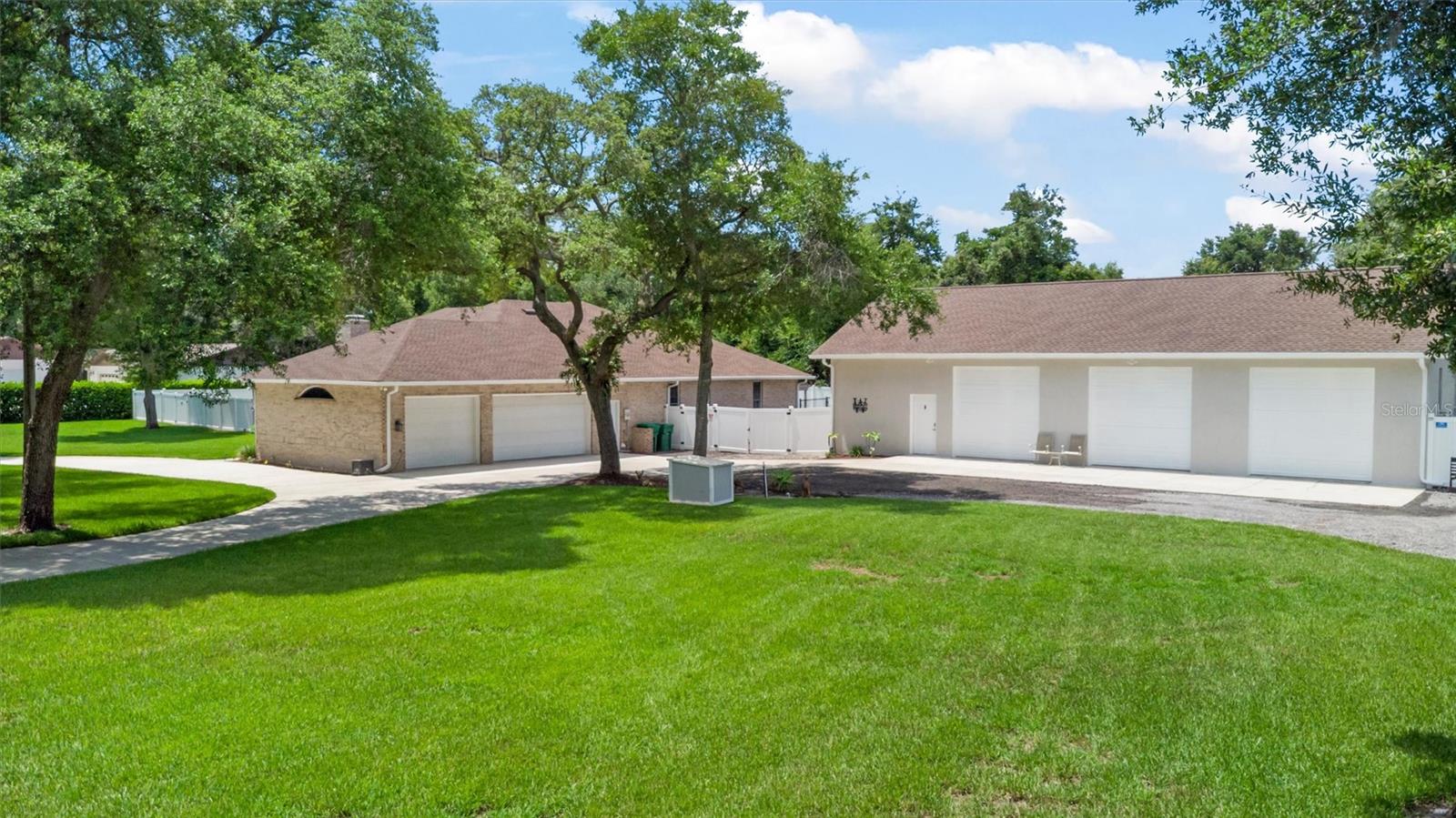 If your toys need their own ZIP code, this might be the one. Welcome to 713 Ernest Drive, a private estate tucked away on more than an acre in sought-after Spruce Creek Estates. This property is the perfect combination of country living within minutes of town, incredible storage, and space for just about every hobby, vehicle, boat, RV, or project imaginable. The main residence offers over-the-top functionality with a spacious split floor plan featuring 3 bedrooms, 3 bathrooms, volume ceilings, a large family room, separate living room, oversized kitchen, generous walk-in pantry, and a dedicated mudroom with laundry. A fourth flex room is currently set up as a bedroom, but could easily serve as a den, media room, playroom, hobby room, guest retreat, or whatever space your lifestyle demands. The primary suite is truly a retreat of its own, featuring a private office, an additional flex space perfect for a nursery, home gym, or sitting area, dual walk-in closets, and a large bathroom complete with double vanities, garden tub, walk-in shower, and private water closet. Beautiful windows throughout the home provide natural light and peaceful views of the surrounding property. Step outside and you'll quickly realize this property offers far more than just a backyard. The saltwater pool, installed in 2023, serves as the centerpiece of an impressive outdoor living space. Its advanced automation system allows you to control lighting, fountains, bubblers, and other features directly from your phone. To one side of the pool is a huge side yard, providing plenty of room for pets, play, entertaining, or simply enjoying the open space. On the opposite side, a pergola-covered hot tub creates the perfect place to unwind at the end of the day. The property has been thoughtfully designed with a fence dividing the acreage into two distinct areas. One side is dedicated to recreation and outdoor living, featuring the pool, expansive fenced yard, covered patio, pergola, and hot tub. The other side is built for functionality, with extensive trailer and RV parking, workshop space, storage areas, and the detached garage complex. This unique layout allows you to enjoy all the benefits of a private backyard retreat while keeping equipment, toys, trailers, and projects organized and separate from the main outdoor living areas.
For those needing garage space, workshop space, storage space--or all three--this property delivers in a way that is nearly impossible to find. The attached oversized 3-car garage measures approximately 27 feet deep by 37 feet wide. Beyond that, a massive detached garage offers three additional bays, a 4-post car lift, loft storage, a dedicated air-conditioned office/workshop with a half bath, a separate workshop area, and RV parking. The fenced compound surrounding the detached garage provides abundant room for trailers, boats, equipment, and additional vehicles. Major updates include a 2022 roof, new HVAC system, and two new water heaters. The property is serviced by city water and septic, while also featuring a private well capable of supplying water to the entire home if needed. Full irrigation keeps the grounds looking their best year-round. Located within the highly desirable school zones of Sweetwater Elementary, Creekside Middle, and Spruce Creek High School, this rare estate offers the privacy of country living with the convenience of Port Orange just minutes away.