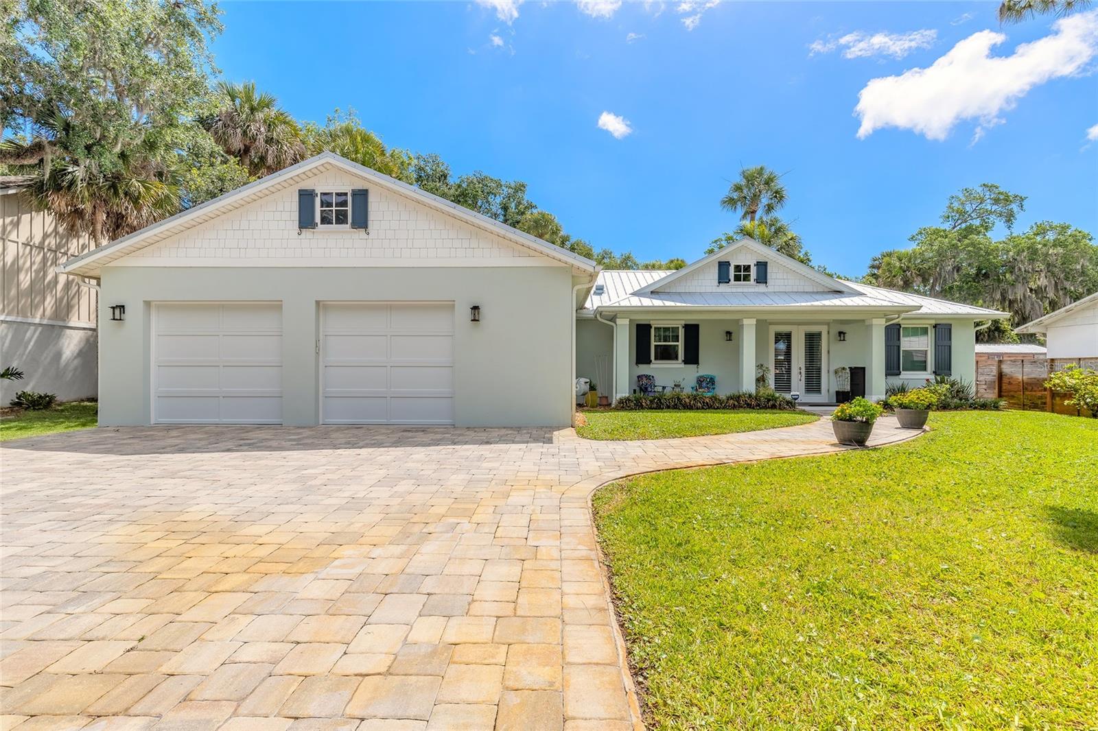 Coastal-inspired living meets quality concrete block construction in this beautifully expanded 2BR/2BA home built in 2018 and thoughtfully enhanced in 2024. From the moment you step inside, the home delivers an immediate “WOW” factor with its spacious open-concept design seamlessly blending the living room, kitchen, dining area, and family room into one bright and inviting gathering space, highlighted by gorgeous vaulted shiplap ceilings throughout the main living areas. Designed with a desirable split-bedroom floor plan, the oversized primary suite features custom built-ins, 2 large walk-in closet, and a private bath retreat. Abundant natural light pours through newly installed hurricane-rated doors and windows accented with 2-inch wood blinds, showcasing the soaring ceilings and soft coastal-inspired color palette throughout the home.
The open kitchen overlooking the Living area is beautifully appointed with granite countertops, stainless steel Samsung appliances, upgraded soft-close cabinetry, and a convenient drawer-style microwave. Additional interior upgrades include dual electrical panels, a spacious mudroom/laundry area with room for an extra refrigerator, and a gas-powered tankless hot water heater. Also includes Marwal electronic cleaning device for whole house assistance.
Outside, major upgrades continue with a durable metal roof installed in 2018, full-house gutters, and an expansive rear deck spanning the entire length of the home, creating the perfect space for entertaining or relaxing outdoors. The fully fenced backyard offers gates on both the north and south sides for added privacy and convenience, with ample room to add a future pool. A well-fed inground sprinkler system keeps the beautifully maintained yard lush year-round. There is a receptable built in for a Generac. 
The oversized 2-car garage includes additional storage space along with a REAR garage door opening to a pavered area behind the home for complete drive thru accessability. A massive 35’ x 12’ freestanding storage building with electric and two separate rooms provides exceptional flexibility for hobbies, workshop space, equipment, or additional storage. The property also features two EV/RV plugs and a house-wide alarm system that can be conveniently programmed from your smartphone.
This move-in-ready property combines modern construction, thoughtful upgrades, exceptional indoor-outdoor living, and a highly functional layout designed for both entertaining and everyday comfort. Conveniently located close to local shopping, the NSB Library, Canal Street activities, and the beautiful beaches of New Smyrna Beach, this well-built fortress is truly a must-see.