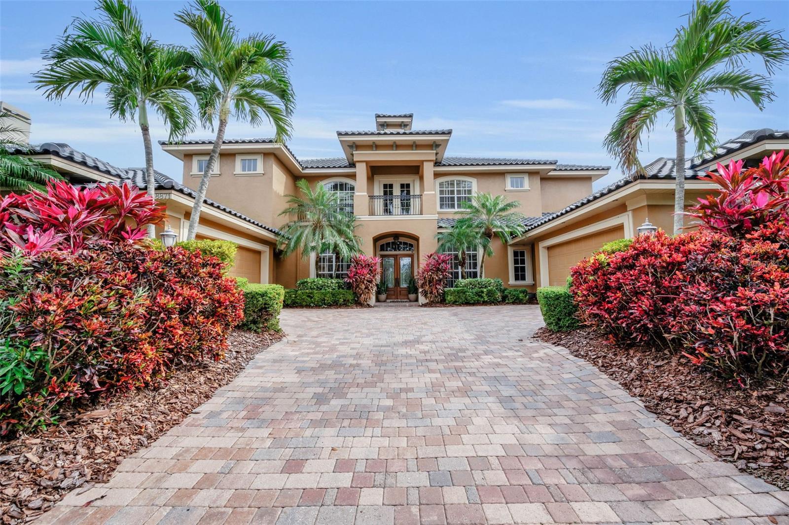 Modern Tuscan revival architecture and thoughtful innovation converge in this exceptional Mediterranean style Luxury custom-built Two story residence in Bayou Club Estates, where openness, comfort, and quiet sophistication define every space. Meticulously designed and exquisitely finished, the home reveals superior craftsmanship from the moment you step inside.  At its heart is a sun-filled, two-story living area framed by a dramatic wall of windows, Tuscan style columns all overlooking the paver terrace and resort-style pool, custom built in 2022. The expansive outdoor environment is designed for effortless enjoyment: a sweeping paver deck ideal for entertaining, a shimmering, new-generation pool that invites relaxation, a putting green and a full-size built-in gas fire pit that sets the tone for memorable evenings under the stars.  Just off the entry, an inviting dining room, enhanced by a custom built-in buffet, flows seamlessly into the living area.  Adjoining the kitchen is a casual dining space ideal for everyday meals form a true culinary hub, featuring chef-grade appliances, custom cabinetry, a large center island, and quartz countertops. Adjacent to the kitchen is a spacious utility room offering abundant cabinetry, a full-size washer and dryer, and generous storage. This highly functional workspace transitions naturally into an inviting family room anchored by a gas fireplace with custom built-ins & huge mantle with a striking architectural window flooding the room with light, creating the perfect setting for both intimate meals and lively gatherings. The light-filled family room offers a year-round retreat with serene views of the gardens and pool.  A split bedroom layout ensures privacy for all. The main level includes a spacious home office, a secondary ensuite bedroom, and a generous flex room—currently used as an exercise studio—with an adjacent full pool bath. Upstairs, the primary suite serves as a calming sanctuary, offering generous proportions, a spa-inspired ambiance, an expansive double walk-in closet and a private second story terrace overlooking the private backyard. A landing between the upper-level bedrooms provides a striking overlook to the lower level and opens to a private terrace with views of the front green space. Two additional bedrooms, connected by a Jack-and-Jill bath, and a dedicated study with integrated shelving complete the upper floor. Set on a large waterfront lot, the backyard is an oasis for everyday living and weekend recreation. A private dock allows for small-craft access to a peaceful waterway that meanders toward the Bay and the Gulf. The fully usable green space offers ample room to play, ideal for both pets and children. Practical luxuries and value added improvements include a new concrete, barrel tile roof, an oversized, split four-car garage, newer kitchen & baths and exceptional storage throughout. Perfectly positioned in the heart of the Largo/Seminole area, the Bayou Club community is comprised of 400 homes on just over 400 acres boasting that “Old Florida” feel and a Tom Fazio designed Golf Course offering an optional membership. This premier Country Club features 24 hour gated security and full-time security guard.  Elegant, functional, and beautifully private, this home embodies the quintessential Bayou Club lifestyle!