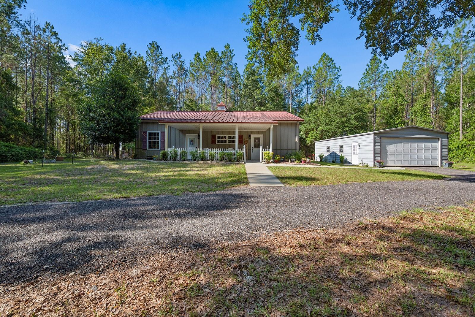 Escape to your own private North Florida retreat with this beautiful 3 bedroom, 2 bathroom metal home situated on 40 acres of planted slash pines in Chiefland, Florida. Located within the gated Winding River Preserve community, this property offers the perfect combination of privacy, natural beauty, and agricultural benefits. The home features a welcoming covered front porch, perfect for enjoying peaceful mornings, along with a screened back porch overlooking the property. Inside, you'll find comfortable living spaces designed for everyday living and relaxing after a day outdoors. Outside, enjoy evenings gathered around the fire pit, grow your own produce in the garden, and take advantage of the large detached two-car garage with plenty of room for vehicles, equipment, or workshop space. The property is zoned Agricultural, and the planted slash pines provide the added benefit of reduced property taxes while offering future timber potential. Winding River Preserve is known for its scenic surroundings, spacious homesites, and peaceful country atmosphere. Conveniently located just minutes from Chiefland, you'll enjoy easy access to shopping, dining, schools, and medical facilities. Outdoor enthusiasts will appreciate being close to the world-famous Suwannee River, Manatee Springs State Park, Fanning Springs State Park, and the Gulf, offering endless opportunities for boating, fishing, kayaking, hiking, and exploring Florida's natural springs. Whether you're looking for a full-time residence, recreational property, or investment in North Florida land, this unique acreage offers the space, privacy, and lifestyle you've been searching for.