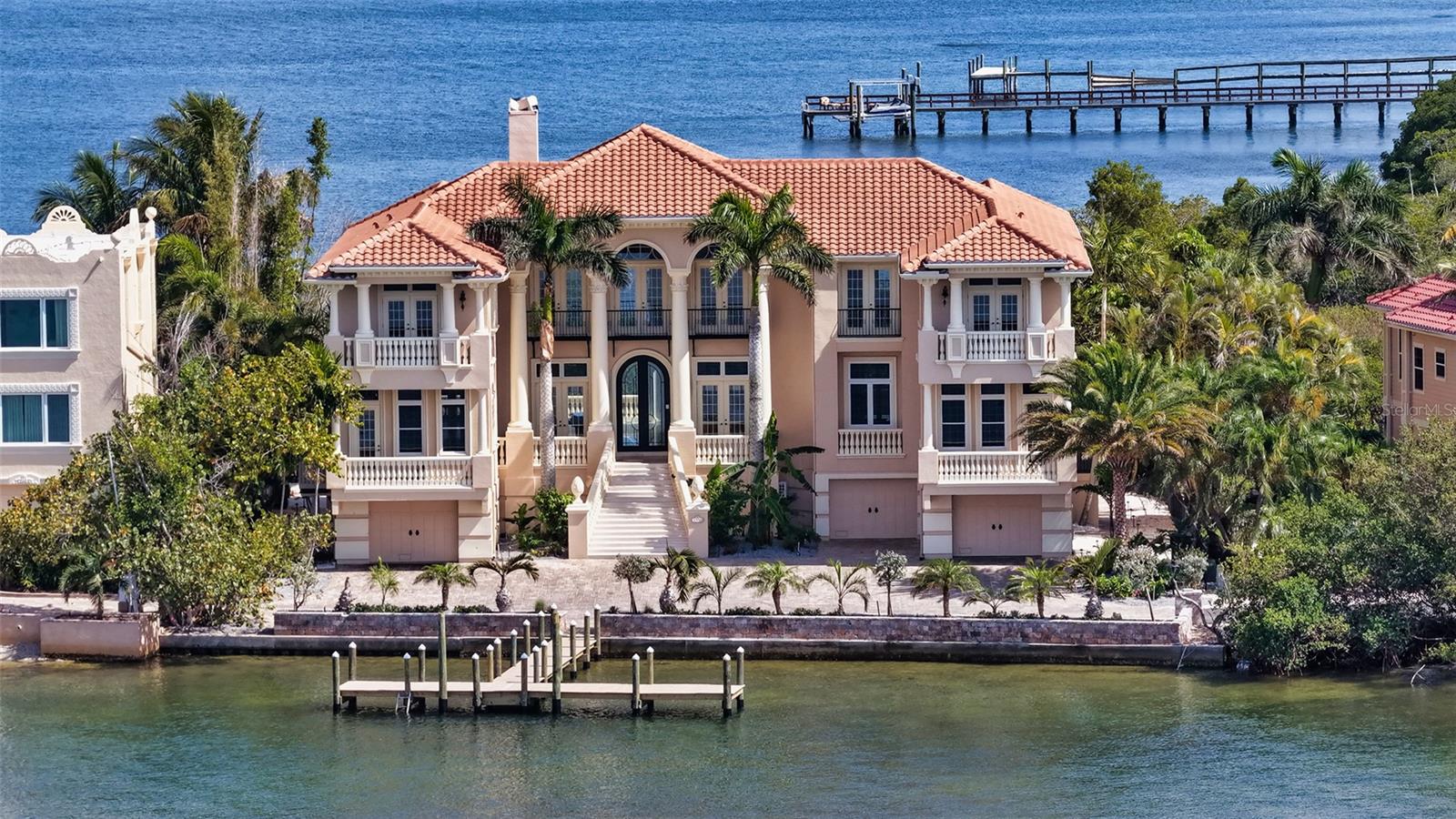 Virtually Staged. Ideally positioned on the exclusive Point Crisp Peninsula of Siesta Key, this waterfront estate offers a rare blend of privacy, scale, and direct boating access, with sweeping views spanning both Little Sarasota Bay and the Intracoastal Waterway. Set on over 230 feet of water frontage, the property features a newly constructed T-shaped dock (2025) and allows for effortless arrival by land or water, all complemented by the rare advantage of nearby beach access.
Spanning more than 7,400 square feet of interior living space, the five-bedroom residence is designed for elevated coastal living, where expansive entertaining areas and walls of glass frame panoramic water views throughout. Freshly painted and ready for personal customization, the two-story interior is defined by high coffered and tray ceilings, crown molding, solid-core doors, and a blend of marble and wood flooring. A grand double-door entry opens to a soaring living area with a cathedral ceiling and statement fireplace, while floor-to-ceiling sliding glass doors create a seamless connection to the outdoor living spaces.
The multi-level outdoor setting is designed for both gathering and relaxation, featuring an extended travertine deck, covered lounge areas, an outdoor gas fireplace, a summer kitchen with built-in grill and wraparound bar, an additional grilling station, and a heated pool and spa—all overlooking the tranquil waterfront.
At the center of the home, the gourmet kitchen was redesigned in 2022 with quartzite countertops, custom cabinetry, professional-grade appliances, and an oversized island with seating. The adjacent family room offers built-in features and direct access to the outdoor entertaining areas, creating a natural flow for everyday living.
The primary suite, located on the main level, serves as a private retreat with expansive water views, a custom walk-in closet, and a spacious en-suite bath. An additional guest suite on this level provides flexibility for a study, fitness room, or nursery.
The second level is dedicated to guest accommodations and recreation, offering a home theater, an oversized game room with wraparound bar, multiple terraces, and three additional bedroom suites—one of which is generously scaled to function as a second primary suite—each with access to outdoor living spaces.
The ground level includes a six-car split garage with multiple storage and utility rooms, supporting both functionality and flexibility.
Located within one of Siesta Key’s most sought-after enclaves, this residence offers the unique combination of close beach access and protected boating waters. Just minutes away, Siesta Key Village provides dining and boutique shopping, while downtown Sarasota offers a vibrant cultural scene with theaters, galleries, waterfront parks, and marinas—delivering a lifestyle that balances coastal tranquility with everyday convenience.