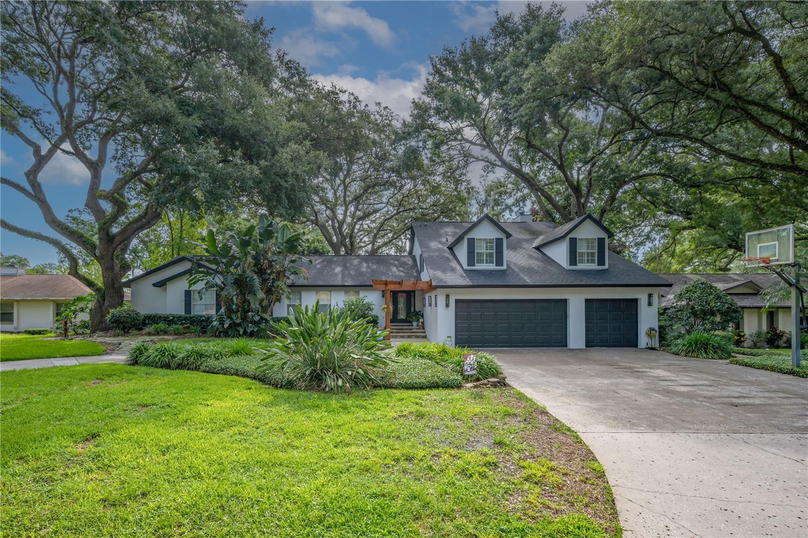 Rare 5 bedroom plus office, 4.5 bath pool home offering over 4,000 sq. ft. of living space on nearly a half-acre with no HOA, a 3-car garage, and a beautiful circular driveway, ideally tucked away near the end of a quiet cul-de-sac just minutes from Temple Terrace Golf & Country Club, the Hillsborough River, and less than 20 minutes from Downtown Tampa. This spacious home offers an exceptional blend of comfort, elegance, and functionality, with beautiful grand oaks lining the surrounding streets. The expansive deep-water pool, lush Florida landscaping, renovated back deck, and private outdoor living areas create the perfect setting for relaxing, entertaining, and enjoying the Florida lifestyle. The exterior has also been recently repainted, adding to the home’s impressive curb appeal. Inside, the family room features a gas fireplace, custom built-in cabinetry, and French doors opening to the pool and gardens. The gourmet kitchen overlooks the outdoor living space and includes a large island, granite countertops, built-in double ovens, stainless steel appliances, prep sink, and in-island beverage fridge. A large family room offers flexible space for gathering, entertaining, dining, or game nights. The downstairs primary suite opens directly to the pool area and features an updated bath with spa tub, separate shower, dual vanity, and customized walk-in closet. The dedicated office with custom built-ins provides an ideal work-from-home setup without sacrificing one of the five bedrooms. Upstairs, a second en-suite bedroom includes a walk-in closet and a completely renovated bathroom with walk-in shower, tub, and custom cabinetry. The Jack and Jill bathroom has also been completely renovated, and the adjoining bedrooms feature custom built-in walk-in closets for tons of extra storage. Hardwood floors flow through the living and dining areas, kitchen, hallways, and staircase, while vaulted ceilings, crown molding, upgraded baseboards, plantation shutters, window casings, and ceiling fans add quality detail throughout. Additional highlights include an oversized laundry room with pool bath access, abundant storage, and hidden walk-in attic space. A rare opportunity in one of Temple Terrace’s most desirable locations!