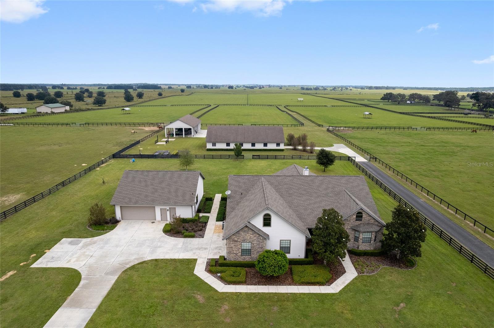 Under contract-accepting backup offers. This turnkey 60-acre farm offers tranquility, top-tier amenities, and unmatched convenience. Under 10 minutes to the World Equestrian Center, 5 miles from Live Oak International, and 20 minutes from Ocala’s premier shopping and dining,  The property is fully fenced with five paddocks, two large pastures, and five shade shelters. The immaculate center-aisle barn features 9 stalls, a full bath, feed/tack room, and wash rack. A spacious workshop with open bays and enclosed storage provides ample room for equipment and trailers. The custom three-bedroom home boasts wood floors, crown molding, and a stone fireplace, plus a chef’s kitchen with island seating, pantry, and wine fridge. The bonus room with wet bar and scenic views opens to a peaceful back patio — perfect for relaxing or entertaining. Move-in ready and ideally located, this property offers the best of Florida’s equestrian lifestyle.