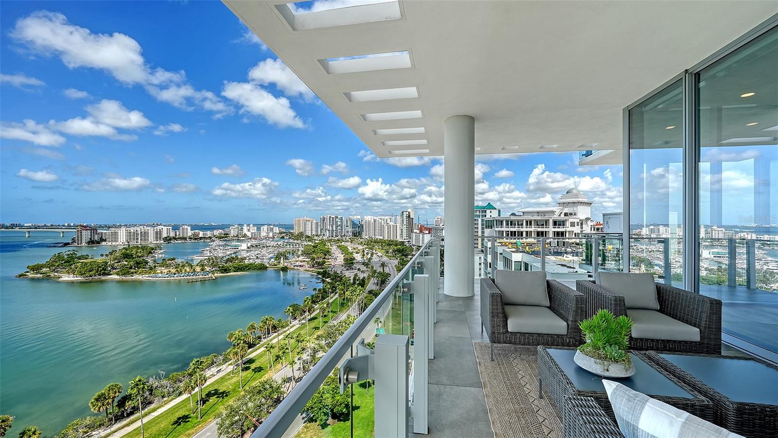 NEW PRICE! Welcome to Epoch—Downtown Sarasota’s most iconic address. 
At Epoch, you will be enveloped in luxury, where architecture becomes art. Inspired by the Sarasota School of Architecture, bringing architectural elements of Brise-Soleil to produce shade and shadows creating beautiful light play and an ambiance that’s unique to each of the 23 bespoke residences. This twelfth-floor masterpiece, built in 2021, offers the entire floor, over 5,600 sq ft of interior space and nearly 2,000 sq ft of wraparound terraces to enjoy panoramic views and spectacular sunsets on Sarasota Bay and The Gulf. The custom design blends the highest level of craftsmanship with secure enhanced hurricane construction, featuring custom floor-to-ceiling 11.5 ft impact sliders that offer unparalleled views, seamless indoor-outdoor living and peace of mind. Esteemed local designer, Studio G, curated this home with sophistication as you take in the sweeping sunsets of Sarasota & Her Islands. Upon entry into the private residence, you are greeted by a custom walnut feature wall complete with Schumacher ™ wallpaper and floating walnut cabinets. The gourmet kitchen boasts Gaggenau™ appliances including a 5 burner gas cooktop, Quartz surfaces, a built-in coffee/juice station, Italian-made cabinetry, a custom walnut dining island and coordinating accent wall. Adjacent to the kitchen is a balcony with an outdoor grill, refrigerator & private seating area. The indoor dining area is highlighted by a custom, hand blown chandelier by Ochre™, offset with additional luxury custom designed lighting throughout the home. Wine connoisseurs will love the 1600-bottle wine room with a cozy tasting area just outside its doors. The Primary suite features panoramic views of downtown with custom 11.5 ft sliders to your private balcony, a walk-in closet & spa-inspired en-suite bathroom. The primary bathroom suite offers a large soaking tub, custom dual floating vanities, Neolith™ porcelain panels, and dual water closets for a truly Zen experience. The three guest rooms enjoy ample walk in closets, en-suite bathrooms & impressive floor to ceiling city views, each with their own terrace. Among the standout features that elevate this residence to true luxury living are a hand-carved onyx powder room sink, a VRF commercial-grade air conditioning system with 4 units, and an RWS™ home water filtration system. Throughout the home, you'll find solid fixtures by Dornbracht™ and Hansgrohe™, along with Toto™ one-piece comfort commodes. A spacious walk-in laundry room with premium Electrolux™ washer and dryer appliances. Additionally, a soundproofed, temperature-controlled room houses the home's network & Control4 system. The property also includes a private three-car garage with an EV charger & generous storage space. Epoch provides world-class amenities: 24/7 security and concierge desk, Resident’s Club gathering room with bar, game tables, wifi & fireplace, a resort style 70-ft lap pool & spa with a summer kitchen, gas grills and fire tables. A dedicated mail and package area for secure deliveries, fitness center, massage suite, steam showers, & a Guest suite. And don’t miss the unforgettable views from the rooftop terrace, with seating for sunset cocktails and stargazing. Located minutes from Marina Jack, Bayfront Park, & Sarasota’s cultural downtown, urban sophistication meets waterfront serenity. Whether entertaining or relaxing, Unit 12 offers a lifestyle that's elevated and effortless.