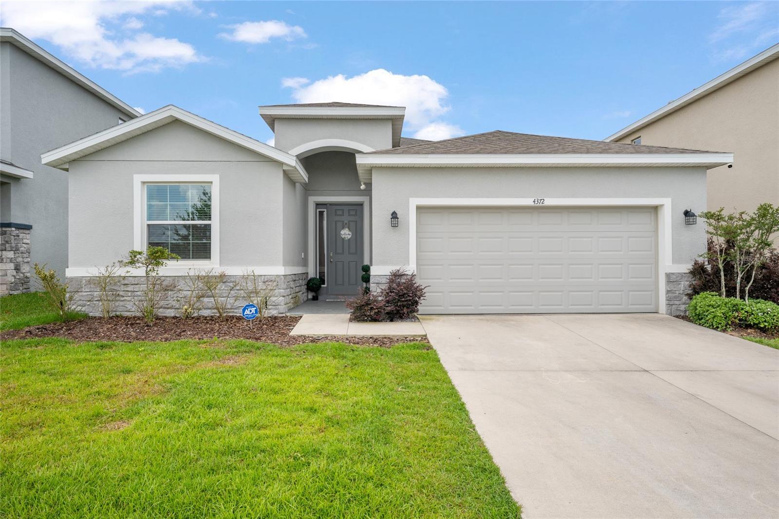 Better than new and built in 2023, this beautifully maintained one-story Lantana Smart Home offers 4 bedrooms, 2.5 bathrooms, and over 2,000 sq ft of open concept living space. Featuring modern finishes throughout, this home includes tile flooring in the main living areas, a spacious living room, and a large kitchen designed for entertaining with granite countertops, subway tile backsplash, stainless steel appliances, walk-in pantry, oversized center island, and white staggered cabinetry with crown molding. The spacious primary suite features tray ceilings, two walk-in closets, and a luxurious ensuite bath complete with dual granite vanities, soaking tub, and tiled walk-in shower with glass enclosure. Secondary bedrooms offer carpet, blinds, and TV mounts, while the additional bathrooms feature granite countertops and tiled tub/shower combinations. Enjoy indoor-outdoor living with a 3-panel sliding glass door leading to the screened lanai with dual ceiling fans overlooking a private backyard with landscaping and a brick privacy wall. The laundry room offers tile flooring and overhead shelving for added storage, and the home also includes a 2-car garage. Conveniently located near shopping, dining, and major roadways, this move-in ready home combines modern style, functionality, and privacy.