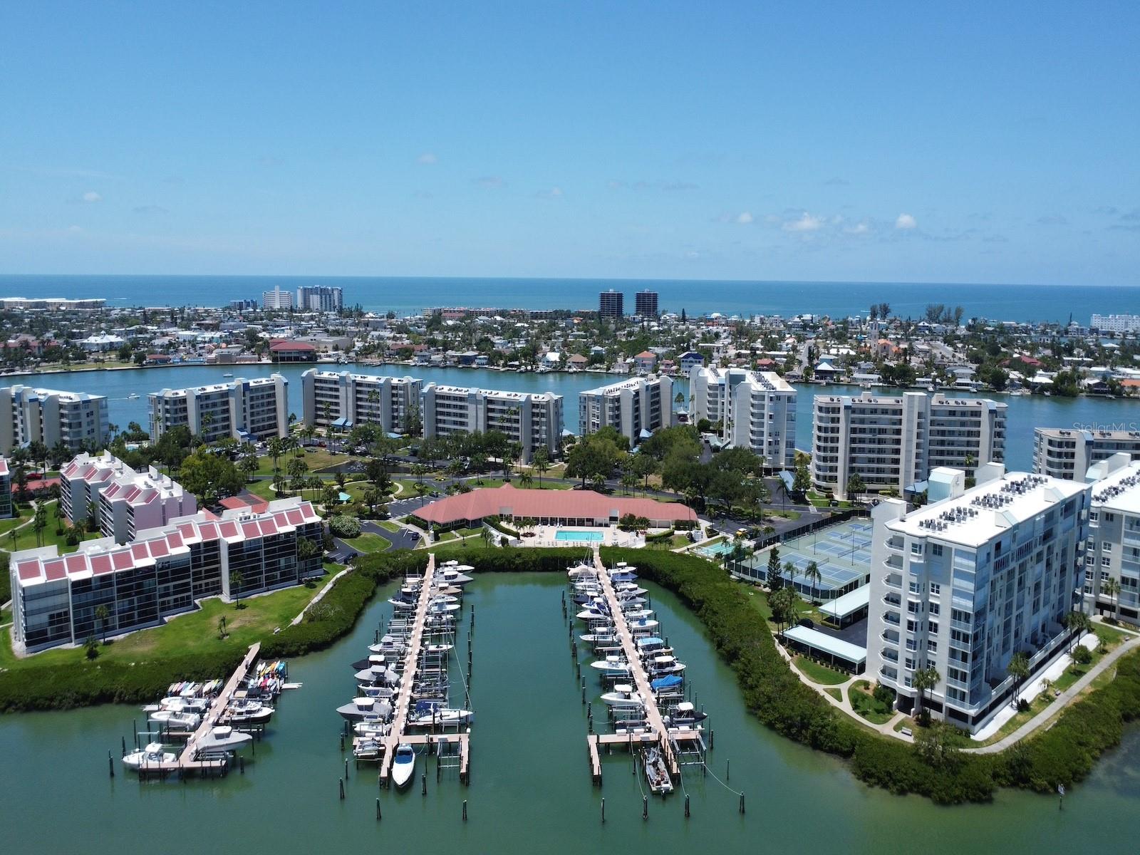 Welcome to Harbourside! St. Pete Beach's premier pet-friendly, 24-hour guard-gated waterfront community. Offering Boca Ciega Bay views, resort-style amenities, and exceptional value, this highly desirable first-floor corner residence presents an outstanding opportunity to enjoy the Florida waterfront lifestyle at an attractive price point.

With nearly 1,500 square feet of living space, this 2 bedroom/ 2 bath residence combines comfort, convenience, and peace of mind with hurricane-impact windows and sliding glass doors, a completed community roof replacement, and easy first-floor access with no elevator required. ROOF 2024, A/C 2017.

Inside, you'll find a bright and inviting interior featuring updated flooring, modern lighting, and abundant natural light throughout. The corner-unit location enhances privacy while showcasing tranquil water views. The spacious primary suite overlooks Boca Ciega Bay and features an updated en-suite bathroom with a granite vanity and walk-in shower.

The enclosed Florida room extends the living space and creates the perfect setting for morning coffee, evening sunsets, or simply enjoying the peaceful waterfront scenery. Accessible from both the living room and primary suite, it offers a seamless connection to Florida's indoor-outdoor lifestyle.

The kitchen has an open concept with granite countertops, shaker-style cabinetry, and stainless-steel appliances, while the adjacent dining area provides an inviting space for everyday living and entertaining. A full-size laundry room with additional storage adds convenience, and the split-bedroom floor plan offers privacy and comfort for family and guests. The residence is vacant and partially furnished, creating an easy opportunity for immediate enjoyment, seasonal use, or full-time waterfront living.

Harbourside residents enjoy an exceptional collection of resort-style amenities, including a waterfront clubhouse, heated pool and spa, fitness center, sauna, tennis courts, pickleball courts, shuffleboard, outdoor grilling areas, and a scenic 1.5-mile waterfront trail winding throughout the beautifully landscaped community. Boating enthusiasts will appreciate the private marina, with boat slips available for purchase or lease, while electric vehicle charging stations and 24-hour guard-gated security provide added convenience and peace of mind.

Ideally located just minutes from award-winning Gulf beaches, waterfront dining, shopping, and vibrant downtown St. Petersburg, this residence presents an outstanding opportunity to enjoy the best of coastal living.

Whether you're seeking a primary residence, seasonal retreat, or waterfront living without the premium price tag often associated with St. Pete Beach, this residence offers exceptional value within one of the area's most established waterfront communities.