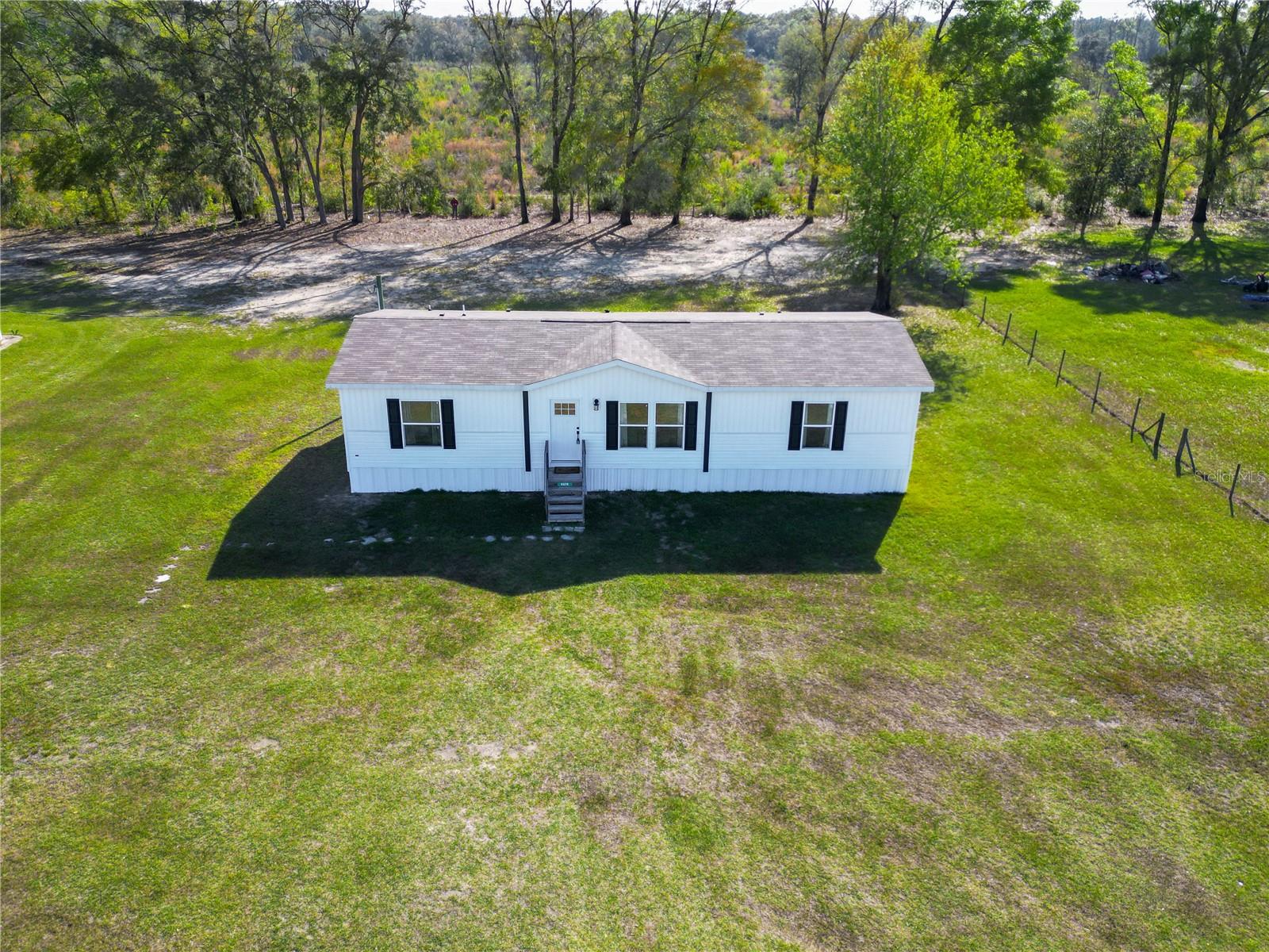 Welcome to 5570 NE 76th Terrace in High Springs, Florida—where modern living meets the natural beauty of North Florida. Built in 2023, this move-in ready, like-new 3-bedroom, 2-bath double-wide manufactured home sits on just over an acre and offers the perfect blend of privacy, space, and convenience.

Tucked away in Gilchrist County, this property features a private setting with no rear neighbors, backing up to protected state land at Blue Springs State Park—creating a peaceful, natural backdrop and long-term privacy that is hard to find. Enjoy quiet surroundings with minimal neighboring homes, where your daily backdrop is nature, not rooftops.

This location is a dream for outdoor enthusiasts. Within minutes, you’ll find Poe Springs, Ginnie Springs, and the Santa Fe River, offering endless opportunities for diving, kayaking, paddleboarding, canoeing, and floating. Live where others vacation and enjoy Florida’s freshwater lifestyle year-round.

Inside, the home offers an open floor plan with a split-bedroom layout, designed for both functionality and comfort. The primary suite provides a private retreat, while the overall layout creates a seamless flow for everyday living and entertaining. This home has been well maintained and presents like new construction, giving buyers the benefits of newer systems, energy efficiency, and low-maintenance ownership.

Situated on just over an acre, there is plenty of room to grow and create your ideal outdoor lifestyle—bring your toys, add a workshop, or design your own backyard oasis. With no HOA and fewer restrictions, the possibilities are wide open.

This is a rare opportunity to own a newer home on acreage with a private, nature-backed setting in a highly desirable area near the springs. Conveniently located within commuting distance to Gainesville, Lake City, and I-75, while still offering the quiet charm of country living.
he home recently had an address update through the county. If GPS has trouble locating it, try using the previous address: 7696 NE County Road 340 High Springs.