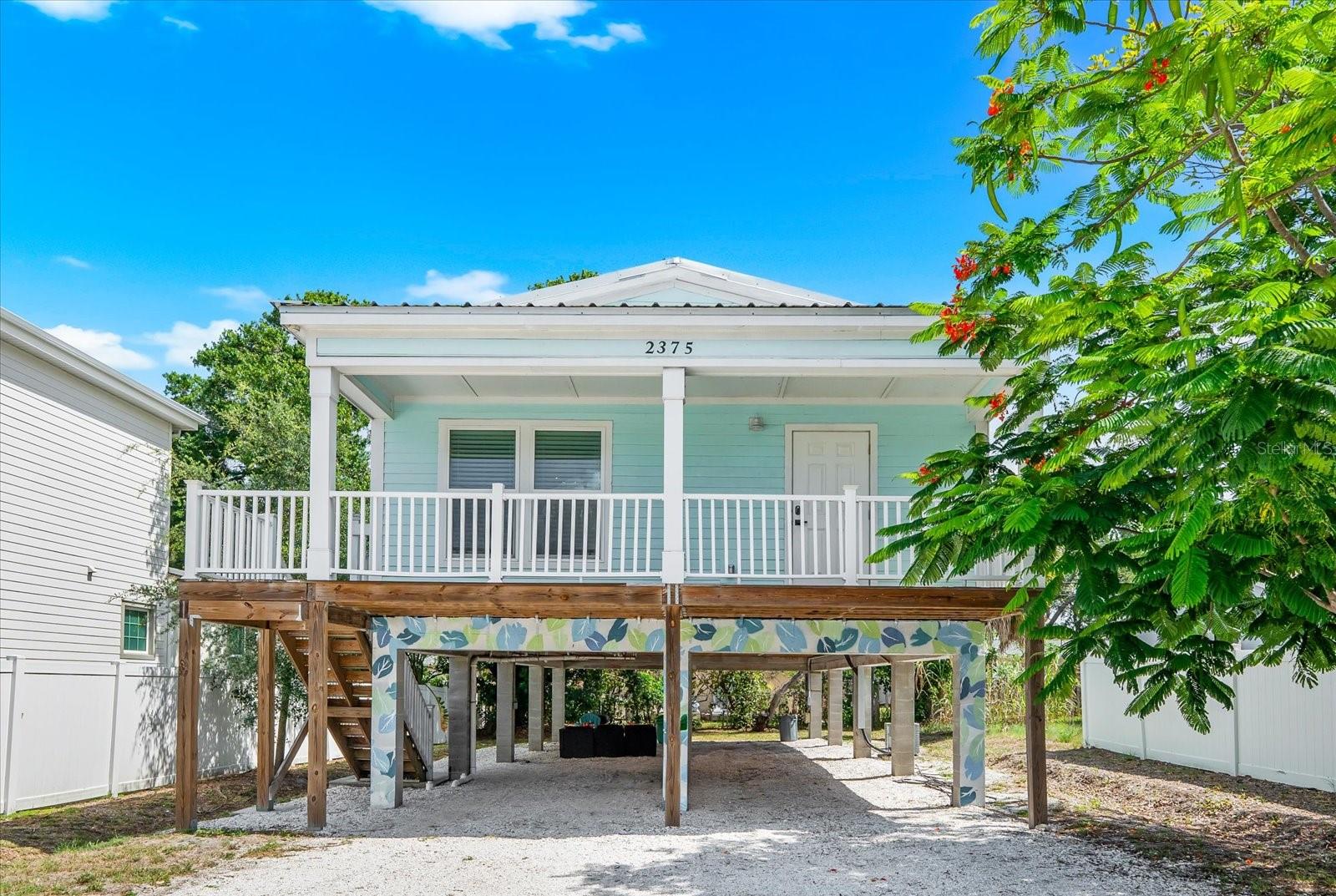 Some homes are built to impress. This one was built to live in — and it delivers on every level. Constructed in 2022 to current building codes, this island-style elevated stilt home sits in one of Sarasota's most coveted in-town corridors, tucked between the energy of downtown and the calm of the Gulf Coast beaches, with virtually everything you need within a half mile of your front door.
Step inside and the first thing you notice is how right it feels. Luxury vinyl floors run throughout, shaker-style cabinetry lines the kitchen, and stone countertops anchor a fully equipped cooking space outfitted with smart Samsung stainless steel appliances. The living room flows naturally into a dining area and a charming alcove complete with an antique bar cart and built-in desk — equal parts functional and full of character. Smart TVs throughout, an interior Samsung washer and dryer, and all turnkey furnishings included mean you walk in and you're already home.
3 bedrooms and 2 full baths sleep up to 8 comfortably, making the layout as practical for a full-time family as it is for a rotating roster of vacation guests. The metal roof and impact windows provide the kind of peace of mind that's hard to put a price on in Florida, and the elevated stilt-on-concrete-piling construction keeps you above the worry. Under-building carport parking accommodates 2 vehicles with ease.
Out back, a serene tree-lined yard gives you a private exhale after everything the neighborhood has to offer — and the neighborhood has a lot to offer. The gym, medical, and pharmacy are each 0.3 miles away. Coffee and groceries are 0.4 miles out. Gas in 0.6 miles, the movie theater in 1.1. Arlington Park and Aquatic Complex — one of Sarasota's most beloved community anchors — is a short walk. Southside Village, with its independent restaurants and neighborhood charm, is right there. Downtown Sarasota, the Bayfront, the marina, the Sunday Farmers Market, the arts district — all within easy reach. Lido Key and world-famous Siesta Key Beach, with its powdery quartz sand, are a quick drive when the Gulf is calling.
Currently operating as a successful short-term vacation rental, this home offers genuine flexibility — use it as a primary residence, a personal retreat, or continue generating rental income with an already-proven property in an always-in-demand location. In Sarasota, that combination is harder to find than it looks.