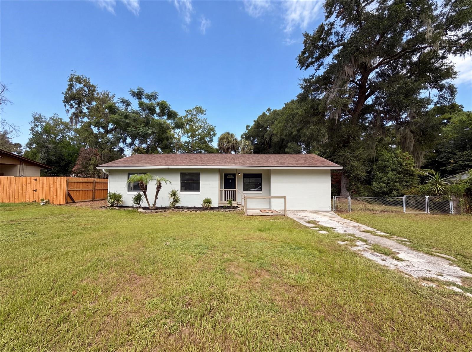 Virtually Staged. 2630 SE 8th Ave is a one-story Ocala home set on a fenced lot with mature shade trees. The kitchen has wood cabinetry, stone countertops, and black appliances, with a breakfast bar that connects to the adjoining living and dining space. Wood-look and carpeted flooring run through the main areas, which stay bright with natural light from multiple windows. Bedrooms are carpeted and comfortably sized, served by full bathrooms that include a soaking tub, a separate shower, and updated vanities. A screened porch off the back extends the living space outdoors, overlooking the open, fenced backyard. Clean, neutral finishes carry throughout, and the single-level layout keeps everyday movement straightforward.. Included 100-Day Home Warranty with buyer activation
