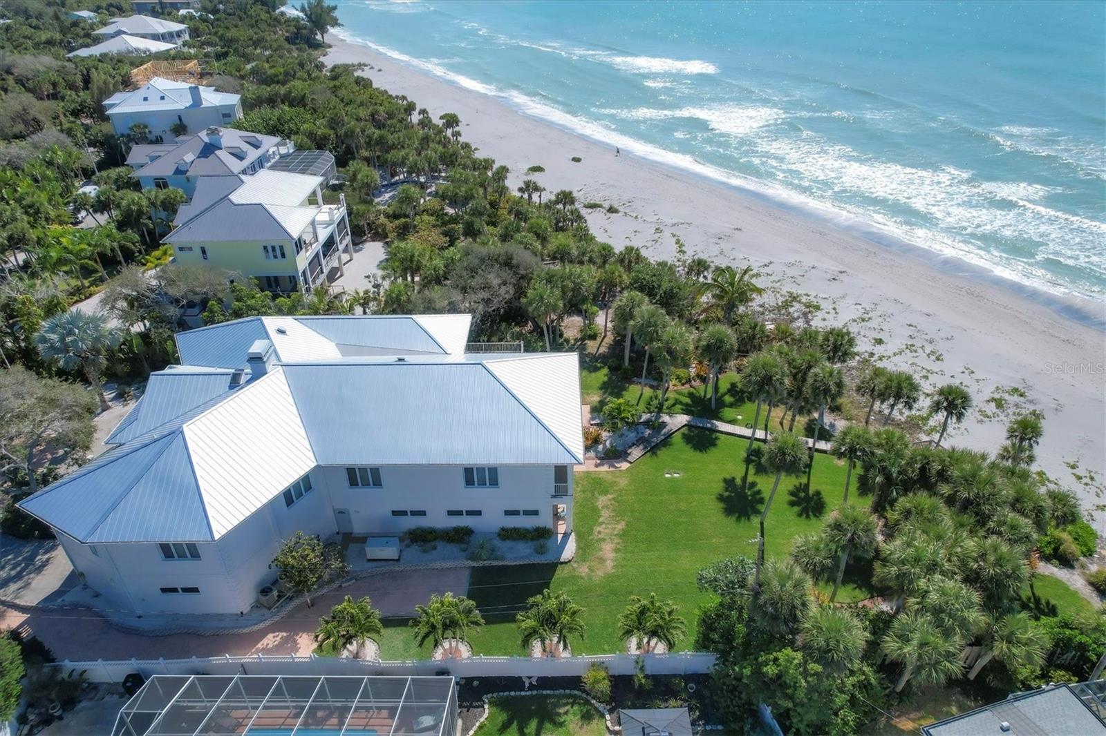 CUSTOM BUILT PRIVATE BEACHFRONT FORTRESS! Situated on one plus acres of gulf front property, this 4 bedroom, 5 bath home has been built with the best construction possible, elevated and reinforced with 52 concrete pilings and concrete walls, the home also features a brand NEW standing seam metal roof, whole house generator and hurricane and lightning protection.  As you enter this secured gated property, and make your way up the grand entrance staircase, or use the elevator from the garage, you’ll be impressed by an exceptional open and bright floor plan featuring high ceilings, custom millwork, heated travertine floors, an immense number of windows and doors allowing you to enjoy the spectacular views of the Gulf of Mexico.  The great room boasts a formal sitting area, gas fireplace, large dining space, well appointed chef's kitchen with custom appliances and top quality finishes, including a wet bar, making this a perfect setting for entertaining. The south wing of the home is where you’ll find the primary bedroom with his and hers custom walk-in closets and a luxurious ensuite bathroom, while the north wing houses an additional three bedrooms, two full bathrooms and your main laundry room.  If you enjoy impressive views, almost every room leads outside to balconies and a large covered deck that extends your living and entertaining to the outdoors, where you can hear the tranquil sound of the gulf waves. The lower level encompasses an expansive 3,000 sq ft, garage with drive through doors, plenty of storage for cars, trailers, golf carts, kayaks and more, and an additional laundry center. Accessed through the garage, or an exterior private door, you’ll find 1,824 sq ft. of additional living space including a family room, kitchenette, three additional (bed)rooms and a full bathroom, which can be used for a mother in law suite, theater room, gym, etc.  Some of the recent upgrades include 3 new a/c units, exterior painting of the entire home, new countertops, light fixtures, new screen on outdoor porch, and several new windows and doors. The home is perfectly positioned on the lot to assure privacy from the road and still have room for a waterfront pool, if desired (pool design plan available on request). Plenty of green space for pets, a play area, putting green or fire pit! Manasota Key is an ideal place to live offering multiple golf courses nearby, tennis clubs, shopping, restaurants, music scene, and some of the world’s best fishing! Don't miss this unique opportunity to indulge in premier beachfront Florida living!
