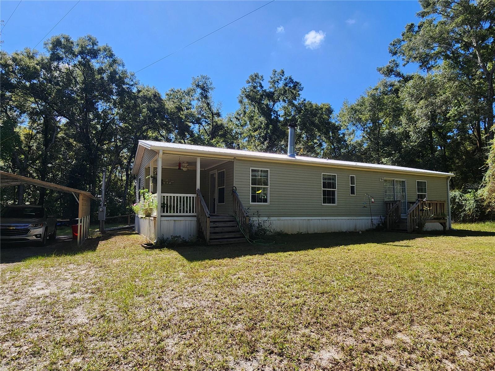 Private Country Retreat! This property features a wooded perimeter that offers 360 degree privacy from the paved road and neighbors. The home and porches are full of charm and offer a cozy oasis. Just over 1 acre in a the Oak Meadows Phase II subdivision that is deed restricted to new doublewides and site built homes with porches and carports. No HOA. Minimal traffic on the backside of the neighborhood with no thru roads. Custom Town Homes 2x6 constructed manufactured home with many upgrades. The home features open living areas, split floor plan, and lots of natural light. Updated Metal Roof and A/C unit are only 3 years old! Updated gutter system. Newer kitchen appliances. Stone fireplace and stove surround detail. Double paned windows and updated entry door. Cathedral ceiling. Large primary bedroom features large closet and good size ensuite bath with walk-in shower. Separate laundry room. Back deck measures 8 x 15 with solid, wood-constructed ramp. Workshop is 22 x 26 with concrete slab, electric, and large sliding door. Detached 20 x 20 double carport. Property features 4 inch well and additional RV hookup. Landscaping includes flowering plants and a butterfly garden. 4 miles from shopping and restaurants in Chiefland. 10 miles to Manatee Springs State Park on the Suwannee River. Located in between Gulf communities for fishing and recreation - 33 miles to Cedar Key and 37 miles to Steinhatchee. 45 miles west of Gainesville.