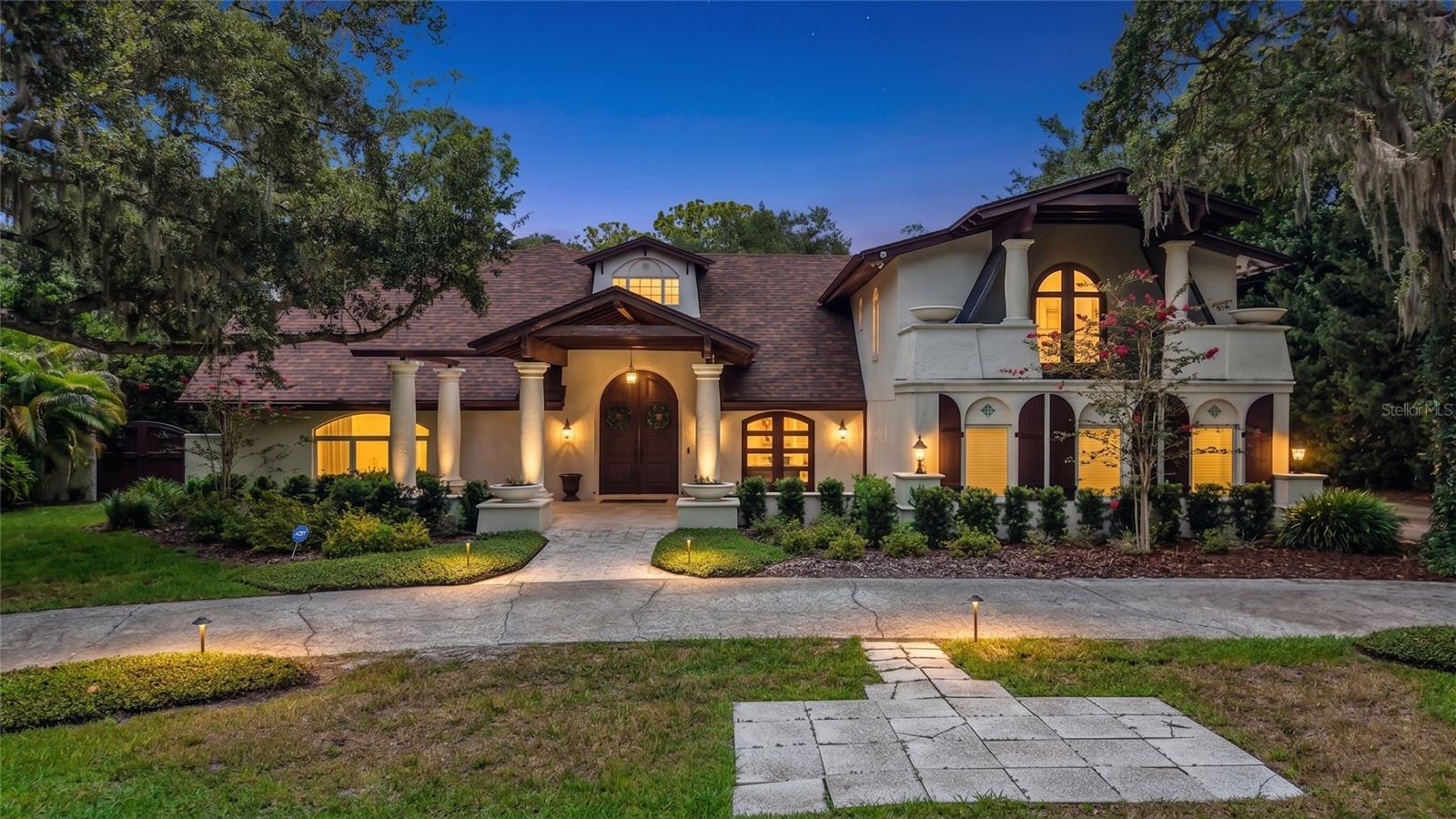 Dunedin - Hidden beneath a canopy of majestic oaks along the peaceful banks of Curlew Creek, this extraordinary Spanish-inspired estate is a rare expression of architectural artistry, timeless craftsmanship, and refined Florida living. Situated on nearly 1.5 secluded acres in the coveted Spanish Trails community, the residence offers almost 5,300 square feet of beautifully curated living space where every detail has been thoughtfully designed to inspire. A private circular drive welcomes you to a home that immediately captivates with authentic character and enduring elegance. Rich reclaimed 114-year-old Pennsylvania oak floors, imported Spanish cedar doors, exposed pecky cypress beams, custom millwork, bay windows, and a magnificent wood-burning fireplace create an atmosphere that is both sophisticated and inviting. Thoughtfully renovated over the years, the home perfectly blends classic architecture with modern luxury. Designed for effortless entertaining and everyday living, the heart of the home is a gourmet chef's kitchen appointed with granite countertops, abundant custom cabinetry, a Sub-Zero refrigerator, and a Wolf gas cooktop. Multiple gathering spaces flow seamlessly throughout the home, while a hidden climate-controlled wine cellar with capacity for approximately 1,000 bottles is sure to impress the discerning collector. The private second level offers five spacious bedrooms, including a serene owner's retreat with two private balconies overlooking the lush grounds and tranquil creek—perfect for enjoying morning coffee or evening sunsets in complete privacy. Step outside to an exceptional outdoor sanctuary. An expansive screened lanai with Spanish tile flooring, a natural gas grilling station, and a granite serving bar overlooks the sparkling pebble-finish pool. Beyond, a freestanding entertainment pavilion with bar seating, an expansive deck, and a children's play area provides endless opportunities for gathering with family and friends. A charming bridge crosses picturesque Curlew Creek, leading to a private secondary green space where towering oaks and mature landscaping create the feeling of your own botanical park. Modern conveniences, including dual-zone Trane HVAC systems, updated electrical, and an oversized attached garage, blend seamlessly into the home's timeless design. Located in desirable Flood Zone X, this remarkable estate offers exceptional privacy just minutes from downtown Dunedin, marinas, boutique shopping, acclaimed restaurants, the Pinellas Trail, and the award-winning Gulf beaches. Homes of this caliber are seldom available. Rich in character, surrounded by nature, and crafted with uncompromising quality, this is more than an exceptional residence - it is a legacy estate. If you've been searching for a home that offers extraordinary privacy, timeless design, and a setting unlike any other in Dunedin, this is your opportunity. Schedule your private tour today and experience the beauty, serenity, and exceptional craftsmanship of 1850 Oak Creek Drive for yourself.