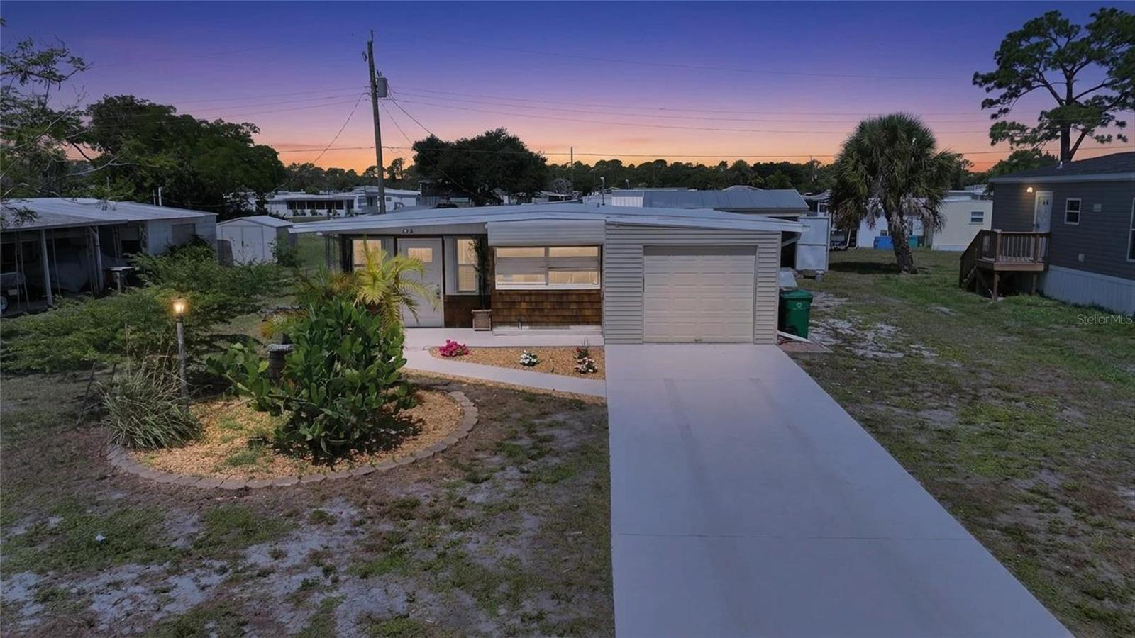 Discover affordable coastal living with exceptional versatility in this well-maintained property featuring a 3-bedroom, 2-bath manufactured home with a rare attached one-car garage PLUS a detached guest house. The main residence offers a bright, open living and dining area, a spacious kitchen with ample cabinetry, luxury vinyl and ceramic tile flooring, and generously sized bedrooms designed for everyday comfort. The detached guest house provides valuable additional living space with its own living area, private room, and half bathroom with a toilet and sink, making it ideal for guests, a home office, hobby space, studio, or flexible-use area. Outside, enjoy an oversized lot with mature landscaping, multiple storage sheds, covered workspace, and plenty of room for gardening, hobbies, or additional storage. The attached garage and expanded concrete driveway provide ample parking for vehicles, boats, or guests. Mobile Gardens is a unique waterfront community where residents have the option to join the low annual HOA, providing access to outstanding amenities including a clubhouse, recreation center, shuffleboard courts, social activities, and two private boat ramps with access to Lemon Bay and the Gulf. Boat slips may also be available on a first-come, first-served basis for an additional fee. Conveniently located just minutes from Englewood Beach, Manasota Key, historic Dearborn Street, local marinas, golf courses, shopping, dining, and the popular Englewood Farmers Market, this property offers the perfect blend of coastal charm, flexibility, and value. Whether you're searching for a year-round residence, seasonal getaway, or investment opportunity, this unique property is ready to fit your lifestyle. Schedule your private showing today!