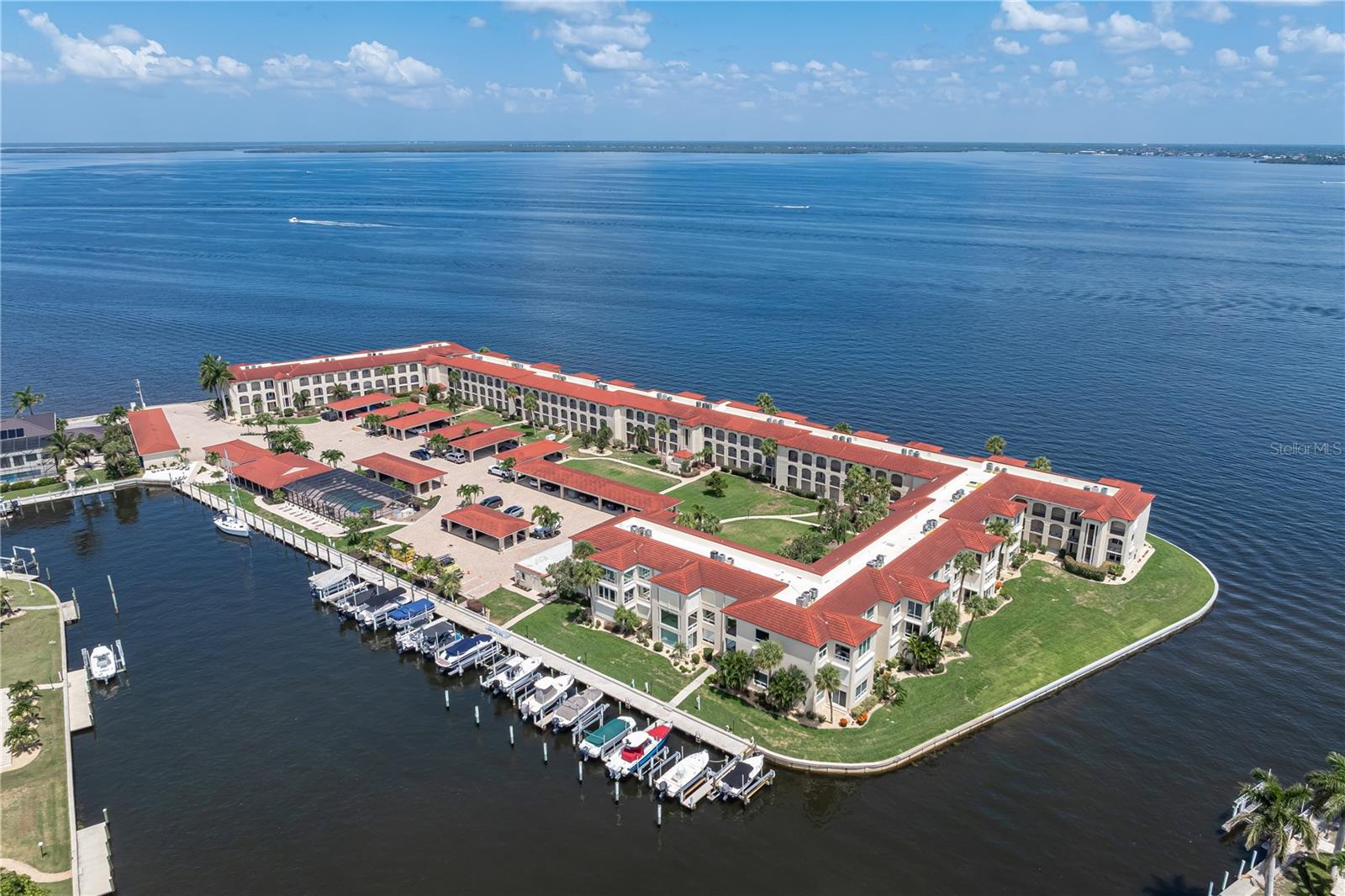 UNOBSTRUCTED HARBOR VIEWS AT COLONY POINT IN PGI - This beautifully updated 2 bed/2 bath condo w/DOUBLE HURRICANE PROTECTION in Punta Gorda Isles overlooks Charlotte Harbor with an unobstructed, PANORAMIC VIEW that stretches for miles. By day, dolphins and passing boats provide an ever-changing backdrop, while spectacular sunsets paint the sky over Charlotte Harbor each evening. Colony Point enjoys a one-of-a-kind peninsula setting where Charlotte Harbor and the surrounding canals create nearly 360-degree water views—an exceptional waterfront setting unlike any other in PGI. From the front door, you'll enjoy a view straight down the canal toward the Marion Ave. bridge, with the community docks and clubhouse in the foreground. Inside, a welcoming foyer with two coat closets greets you opening to the spacious, open floor plan that keeps the harbor view front and center. Large impact-resistant windows frame the spectacular water view while filling the condo with natural light. Electric roll-down hurricane shutters along the back provide added peace of mind. Scraped hickory hardwood plank flooring flows throughout the main living areas, while new carpet adds softness and comfort to both bedrooms. A soft coastal color palette and custom sheer drapery complete the inviting interior. The beautifully remodeled kitchen blends modern design with exceptional functionality. Wellborn cabinetry with soft-close drawers is paired with quartz countertops, a designer backsplash, under-cabinet lighting, and an island with additional storage. Stainless steel GE Café appliances complete the space, while the open layout keeps you connected to the dining area, living room, and the spectacular harbor view beyond. Just beyond the kitchen, the laundry room doubles as a convenient butler's pantry with a second entrance to the unit. Laundry area offers upper and lower cabinetry, a built-in desk, utility sink, stacked washer and dryer, and a closet pantry, creating exceptional storage and workspace in one well-organized area. The enclosed, tiled Florida room extends the living space and offers a front-row seat to Charlotte Harbor where you can enjoy your morning coffee, watch dolphins play and boats cruise by throughout the day, or take in another spectacular sunset. The spacious primary suite enjoys amazing harbor views and features an en-suite bath with walk-in shower. The generously sized guest bedroom enjoys private access to the updated guest bath. Both bathrooms have been renovated with raised ceilings, recessed lighting, updated vanities, and tiled flooring. Residents of Colony Point enjoy beautifully maintained waterfront grounds with newly updated landscaping throughout the community. Amenities include a beach-like seating area with Adirondack chairs overlooking the canal, a screened and heated community pool, clubhouse for social gatherings, bike storage room, floating dock/kayak launch, and a 420-foot concrete dock with immediate sailboat access to Charlotte Harbor. Dock spaces are available on a first-come basis when available. Ideally located just minutes from the Isles Yacht Club, Fishermen's Village, and historic downtown Punta Gorda, this home places waterfront dining, boutique shopping, parks, and year-round events within easy reach. **Claim your spot on the harbor and start enjoying the waterfront lifestyle that makes Punta Gorda so special.**