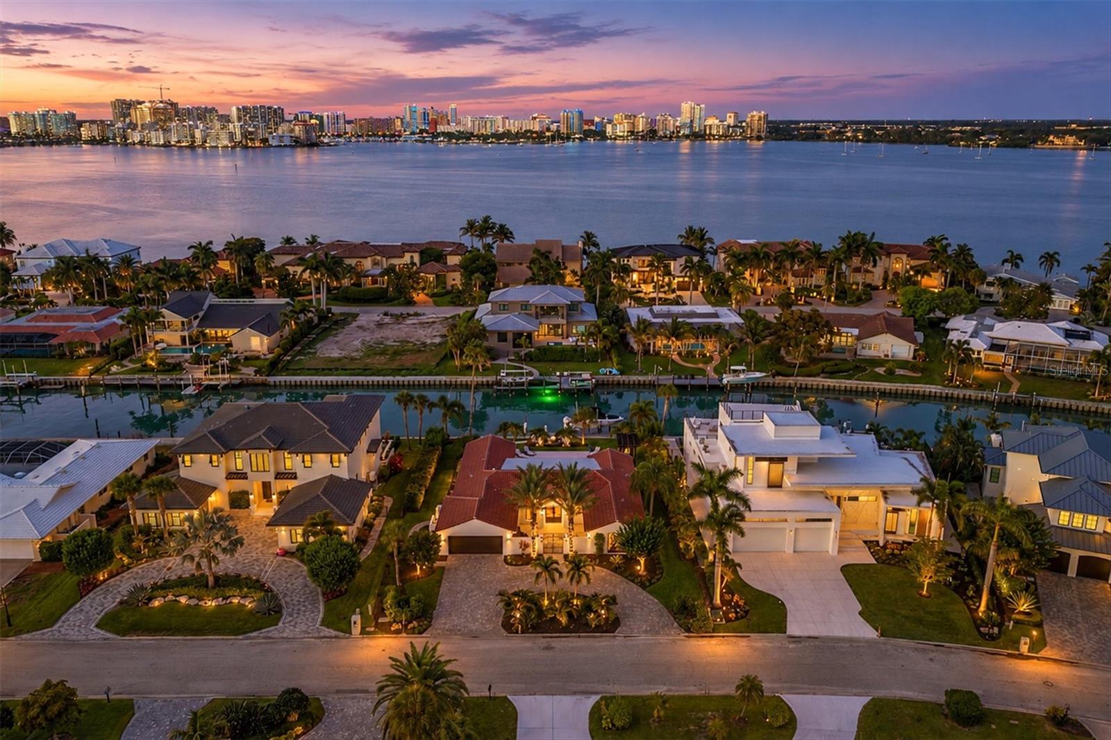 Perfectly positioned on coveted Bird Key, 465 E Royal Flamingo Drive captures the essence of refined Sarasota waterfront living with an extraordinary full renovation that blends timeless coastal elegance with exceptional craftsmanship. Set along 100 feet of protected canal frontage with direct access to Sarasota Bay, this remarkable residence offers an unparalleled boating lifestyle complete with a private dock and 16,000-pound boat lift, creating the ideal setting for effortless days on the water. Encompassing 2,846 square feet of thoughtfully curated air-conditioned living space with four bedrooms and four beautifully renovated bathrooms, every detail of this home has been elevated to deliver a move-in ready luxury experience. Inside, Mirage engineered hardwood flooring flows seamlessly throughout, complemented by new interior and exterior lighting, recessed lighting, designer ceiling fans, and carefully selected finishes that create warmth and sophistication. The spectacular chef’s kitchen serves as the centerpiece of the home and features custom cabinetry with integrated lighting and soft-close doors and drawers, stunning quartzite countertops and backsplash, decorative tile accents, a custom hood, farmhouse sink, premium plumbing fixtures, separate water filtration faucet, Sub-Zero refrigeration with water and ice, wine refrigeration, and an exceptional Wolf appliance package including a six-burner gas range with grill, double convection wall ovens, and additional culinary conveniences. A beautifully appointed butler’s pantry and utility room enhance functionality with a Wolf microwave, KitchenAid ice maker, and Electrolux washer and dryer. Entertain effortlessly with a custom dry bar showcasing illuminated glass cabinetry, quartzite surfaces, and designer tile details. The great room is equally impressive, anchored by dramatic wood beam ceilings, an elegant electric fireplace, and custom built-ins with illuminated shelving that create an inviting yet elevated gathering space. The luxurious primary suite is designed as a private retreat with sliding glass doors opening to the lanai, a spacious custom walk-in closet, and a spa-inspired bath featuring a freestanding soaking tub, floating dual vanity, rain shower, niche detailing, and exquisite finishes of marble and porcelain. Outdoor living is equally exceptional with an expansive lanai finished in shell stone, tongue-and-groove ceilings, electric roll-down screens, and multiple entertaining spaces overlooking the heated saltwater pool and spa, beautifully resurfaced with glass waterline tile, a shell stone pool deck, and pergola. Additional highlights include a fully fenced and professionally landscaped yard with irrigation and landscape lighting, a new clay barrel tile roof completed in 2024, Aluminum ES impact windows and doors, natural gas service, Lennox air-conditioning, dual Rheem gas tankless water heaters, updated paint throughout, seawall enhancements with replacement panels, cap and tie-back system, and an oversized two-car garage featuring epoxy flooring, custom cabinetry, mini-split air conditioning, Tesla charger, and an exceptional level of finish rarely found. This is Bird Key waterfront living at its finest—where luxury, comfort, and effortless access to Sarasota’s world-class boating and downtown lifestyle come together in one extraordinary residence.