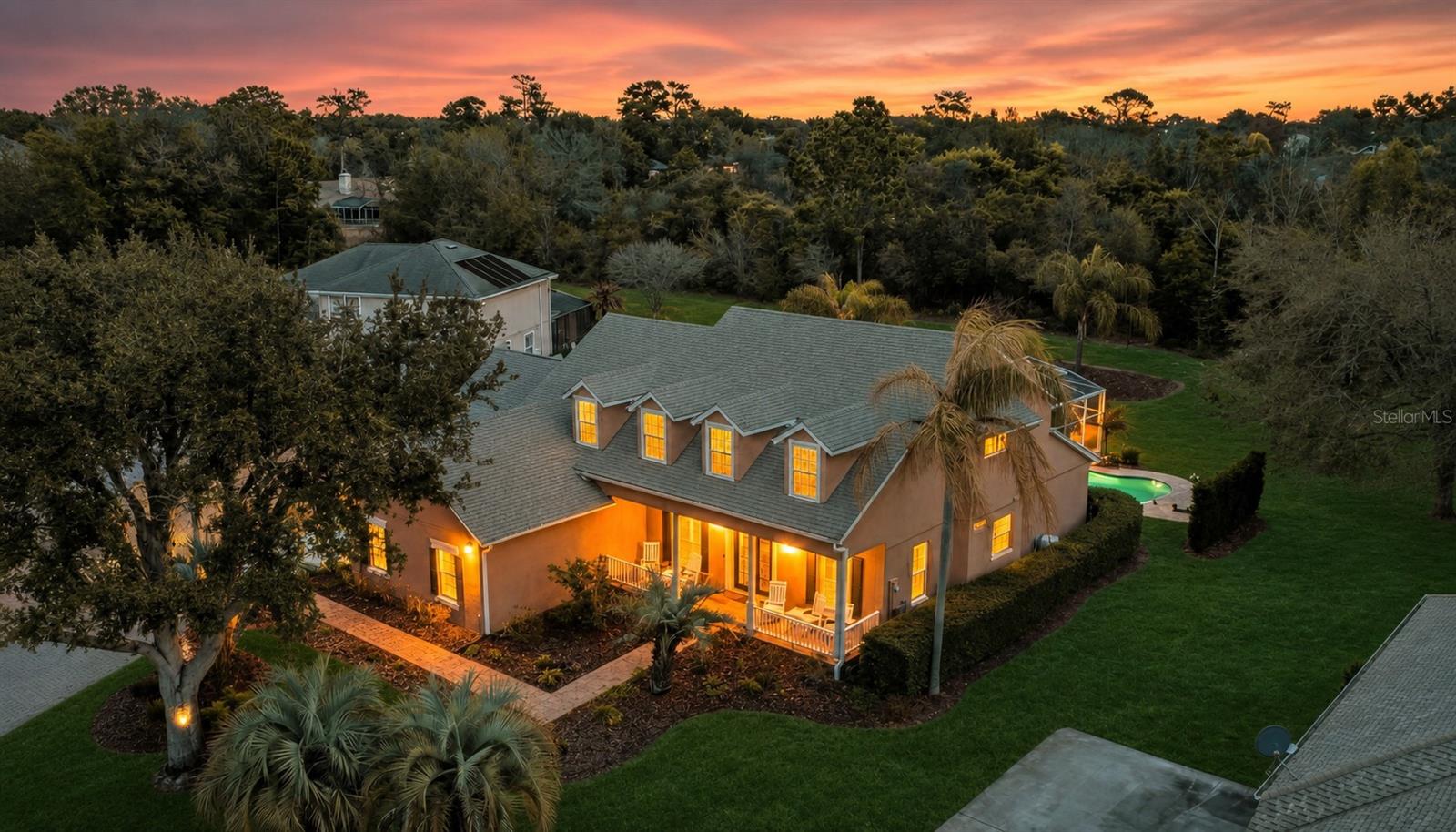 One or more photo(s) has been virtually staged. Here is the spacious, quality-built home you've been waiting for, a traditional two-story Cape Cod with a full front porch, gracefully perched on a scenic knoll near the end of a quiet cul-de-sac in the exclusive gated Glen Abbey Club. With its striking curb appeal, private conservation views, and an expansive four-car garage, this home combines timeless architecture with thoughtful modern updates. Inside, the residence offers five bedrooms and four full baths, beautifully appointed with real wood flooring, detailed crown molding, plantation shutters, and an elegant wood staircase. The living area is highlighted by a ledger-tiled fireplace that creates a warm, inviting centerpiece. Just off the entryway, the private office with custom cabinetry provides the perfect setting for work or study. The designer kitchen is both stylish and functional, featuring a double oven, granite countertops, stone ledger tile accents, a large island, generous storage, and a convenient built-in desk space. Off the kitchen, a spacious workroom and a separate stairway leading to the bonus space above the garage provide excellent climate-controlled storage and versatile workspace options. The first-floor owners' suite offers a cozy fireplace and a luxurious bath with dual sinks, a jetted soaking tub, and an updated tiled shower, the ideal retreat at the end of the day. Upstairs, a comfortable second family room offers additional space for relaxation or entertainment. Every detail has been thoughtfully maintained, with recent upgrades including a new roof completed in 2025, a water heater replaced in 2022, and dual HVAC systems, the upstairs unit installed in 2021 and the downstairs in 2022, both featuring UV light purification systems. Both garage door systems were updated in 2020, ensuring efficient and dependable operation. Step outside to a deep covered lanai designed for effortless outdoor living, where you can enjoy the heated pool and spa overlooking peaceful conservation views. The front porch adds to the home's classic charm, inviting you to settle into a chair, take in a stunning sunset, and feel truly at home. This remarkable home is a perfect blend of classic Cape Cod elegance, modern comfort, and meticulous care, all set within the distinguished community of Glen Abbey Club in DeBary.
