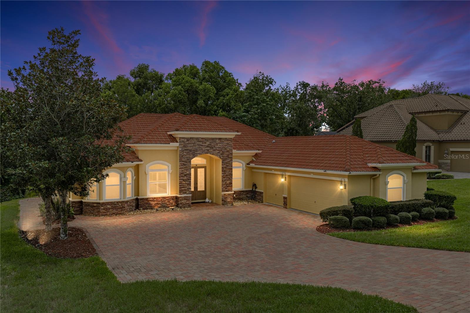 Perfectly positioned on a generous 1/2-acre lot within the gated community of Lake Jovita, this exceptional 4-bedroom, 3-bath home with a dedicated office and a 2-car plus golf cart garage offers 3,049 square feet of thoughtfully designed living space. Complete with a private wooded backdrop, sparkling screened pool, outdoor kitchen, and a brand-new roof being installed within the next few weeks, this home delivers the Florida lifestyle you've been searching for. A paver driveway, mature landscaping, and a covered entry create a welcoming first impression. Inside, double front doors open to a grand foyer flanked by elegant formal living and dining rooms. Tray ceilings, plantation shutters, decorative wainscoting, and wood flooring throughout most of the home add timeless character and warmth. The formal living room features a custom accent wall and a door that frames beautiful views of the pool and outdoor living space. At the heart of the home, the upgraded kitchen seamlessly connects to the spacious family room, making it ideal for everyday living and entertaining. Rich wood cabinetry, stone countertops, a center island with storage, breakfast bar seating, stainless steel appliances, a decorative backsplash, generous pantry space, and a charming pass-through window to the formal living room combine style with functionality. The adjoining family room features a tray ceiling, oversized ceiling fan, and French doors leading directly to the lanai. A private office near the front of the home provides the perfect space for working remotely, studying, or managing daily life without sacrificing a bedroom. The split-bedroom floor plan offers exceptional privacy. The primary suite overlooks the peaceful backyard and features wood flooring, two walk-in closets, and a spacious ensuite bath with dual vanities, a soaking tub, walk-in shower, and private water closet. Bedrooms two and three share a full bath, while the fourth bedroom is tucked toward the rear of the home beside a third full bathroom, creating an ideal guest suite or multigenerational living space. The screened outdoor living area is designed for year-round enjoyment. Prepare meals in the outdoor kitchen featuring a built-in grill, sink, and mini refrigerator, relax under the covered lanai, cool off in the sparkling pool, or simply enjoy the peaceful wooded backdrop that provides exceptional privacy and a true retreat-like setting. Additional upgrades include an owned 250-gallon propane tank, tankless water heater, water softener, reverse osmosis system, French drain system, whole house generator, and a high-end pool vacuum. Living in Lake Jovita means enjoying gated security and outstanding community amenities, including scenic rolling hills, walking trails, a playground, pickleball courts, a basketball court, and a dog park. Optional memberships to the Lake Jovita Golf & Country Club provide access to two championship 18-hole golf courses, a junior Olympic-sized swimming pool, tennis courts, a fitness center, restaurant, and additional social amenities. Schedule your private showing today and discover this beautifully upgraded pool home in one of Dade City's most sought-after communities.