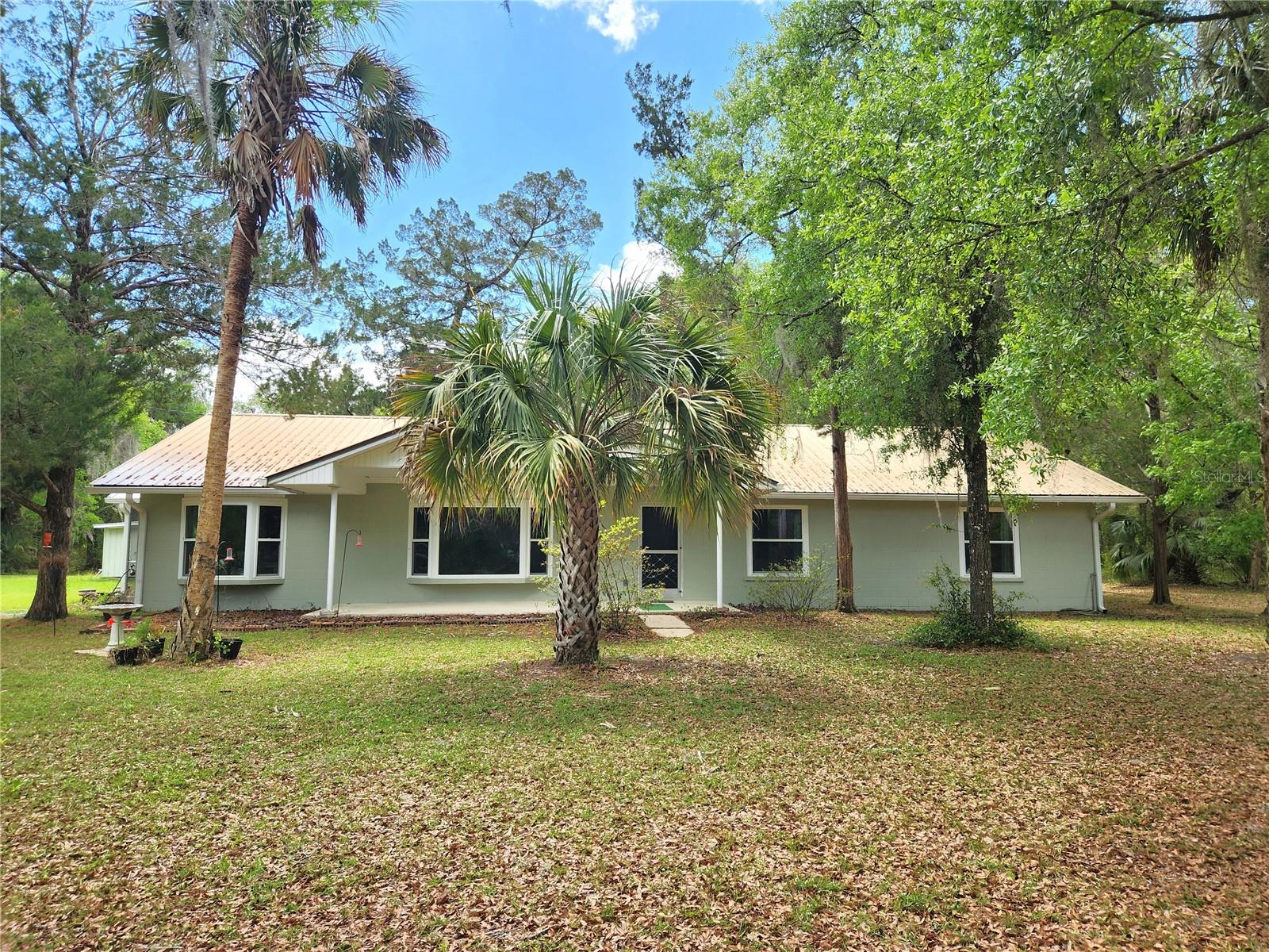 This completely remodeled 3 bedroom, 2 1/2 bath country home sits on 5.43 acres and includes a detached garage/workshop and a pole barn. The home has undergone numerous updates since 2020 including new windows, new A/C unit, new 200 amp electrical panel, new kitchen cabinets and countertops, new appliances, remodeled bathrooms, new light fixtures and flooring throughout. The spacious living room features a bay window that's perfect for watching the birds and deer. The kitchen is light and bright with an abundance of cabinets and an eat-at bar. The extra large primary suite offers a walk-in closet, a double sink vanity and a tiled step-in shower. Guests will enjoy 2 generous size bedrooms with walk-in closets plus double sinks and a tiled shower in the guest bathroom. A bonus room currently serves as a 4th bedroom but would be ideal for a home office. Additional features include a half bath off the kitchen and an inside laundry area with the washer and dryer included. Two screened porches offer the perfect space to relax and enjoy the outdoors. In the backyard you will find a storage building that not only offers ample storage space but also includes double doors to easily park a mower or ATV. The oversized garage/workshop is large enough to accommodate your hobbies and still provide plenty of room to store all your toys. For easy access, a garage door opener operates two of the roll-up doors. Beside the garage is a pole barn providing additional covered storage. The property has paved road frontage with an electric gate and is conveniently located between Ocala, Gainesville and Palatka. Less than 2 miles to the Orange Springs boat ramp on the Ocklawaha River where you can enjoy endless hours kayaking, boating and fishing. Furniture package can be purchased separately.